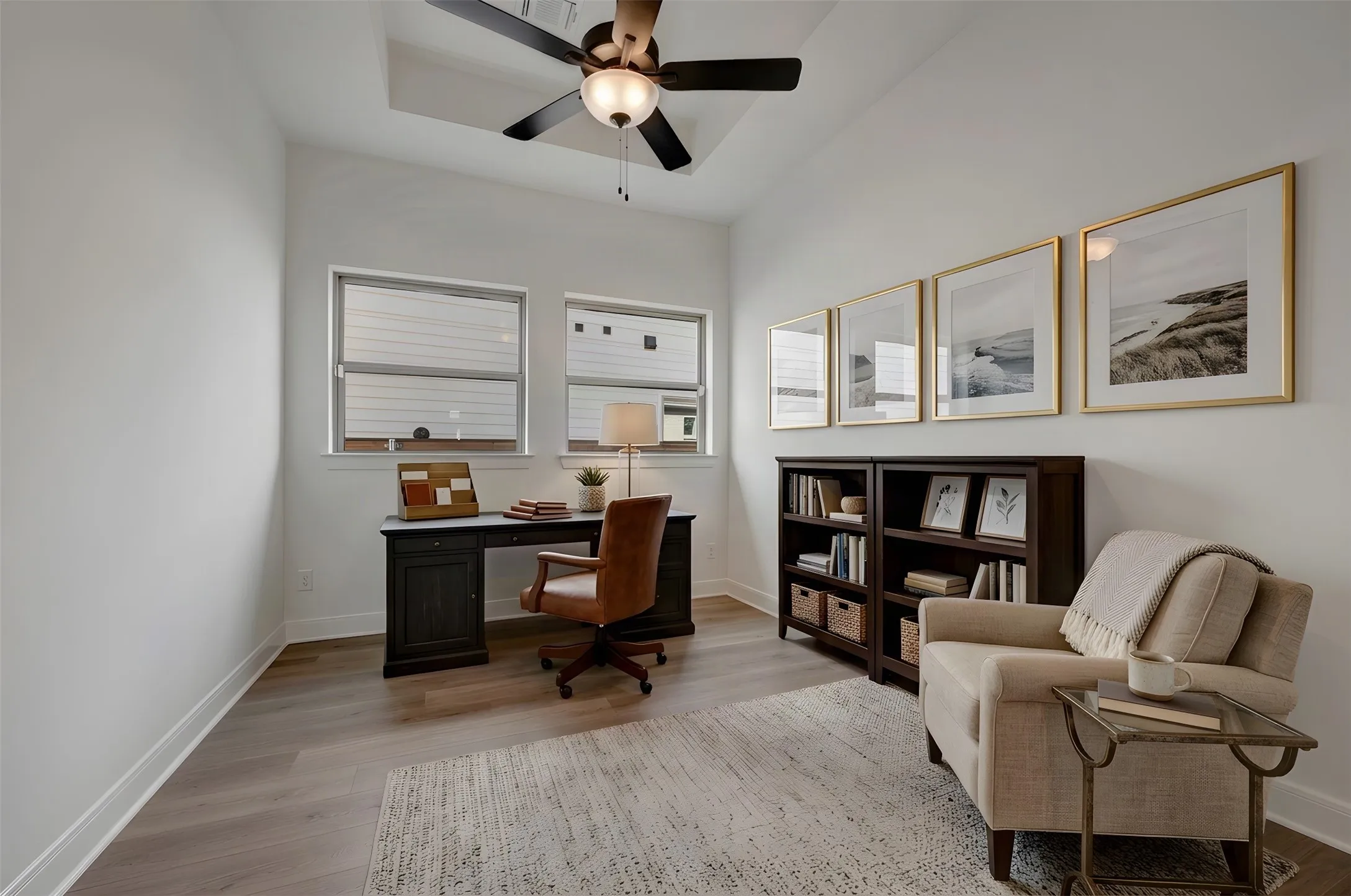 Vaulted ceiling with a ceiling fan, dual windows, wood-finish flooring, and built-in shelving units