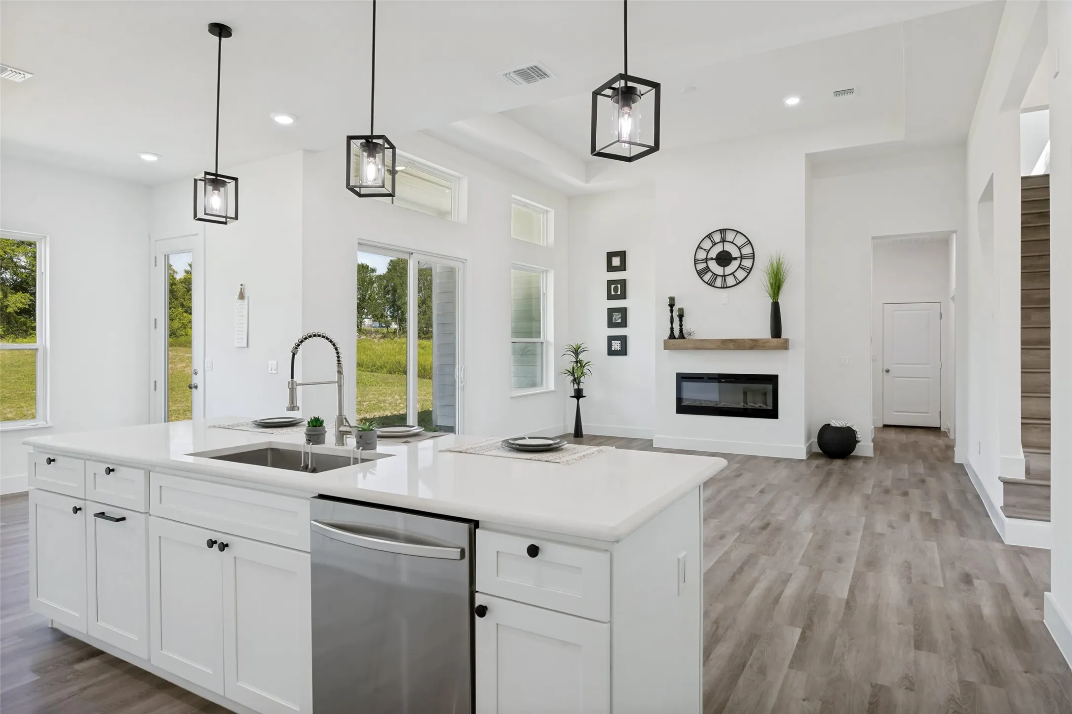 Spacious open-concept interior featuring a bright white kitchen island with an integrated sink and stainless steel dishwasher