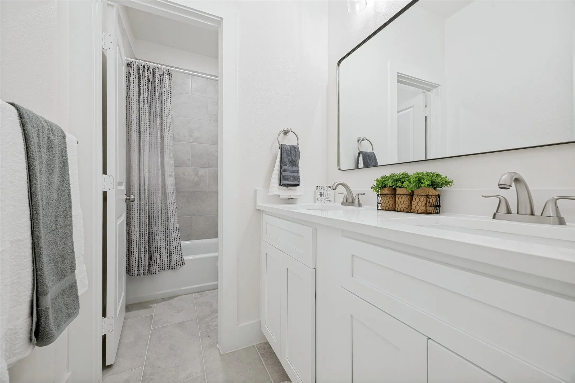 Dual sink vanity with white cabinetry, a light-toned countertop, and brushed nickel faucets