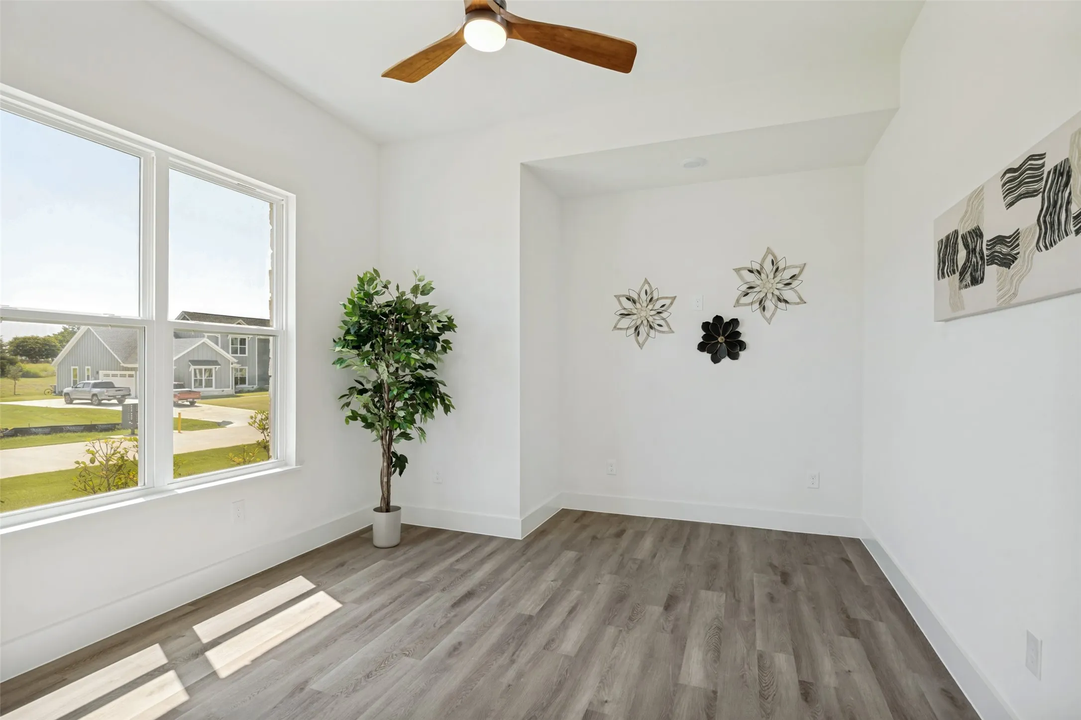 Bright room featuring abundant natural light from a large window, a wood-finish ceiling fan, recessed lighting, and modern wood-finish flooring