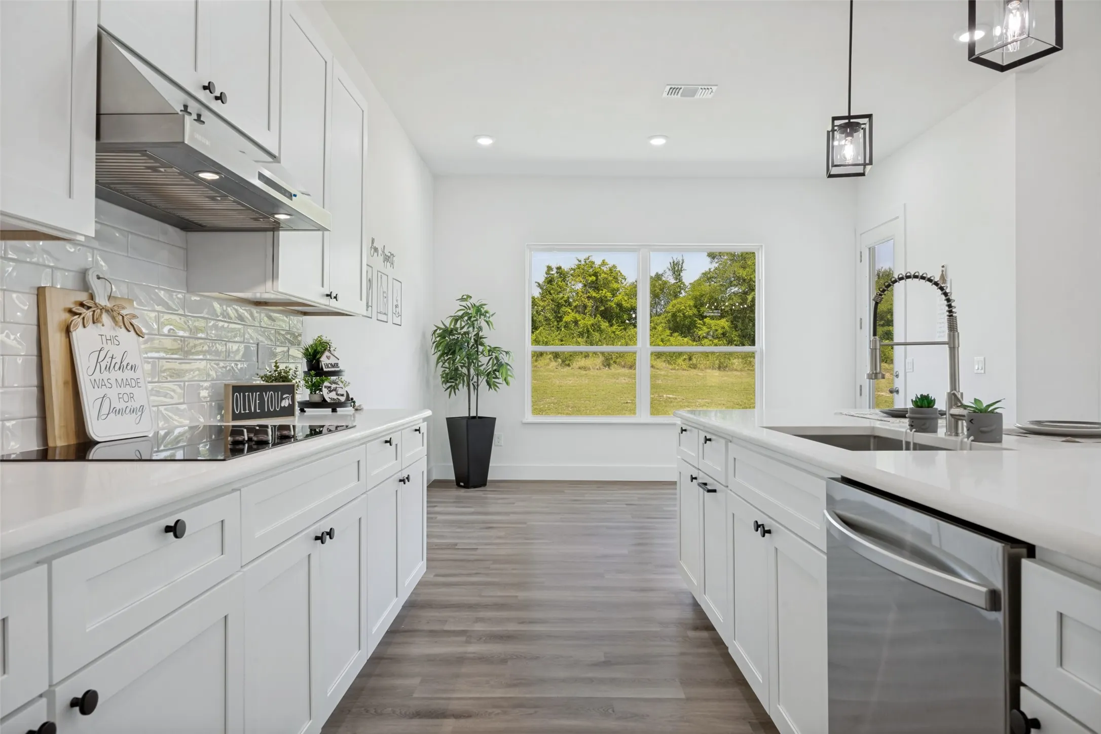 Modern kitchen featuring white shaker cabinetry, stainless steel appliances, a subway tile backsplash, light countertops, and wood-finish flooring