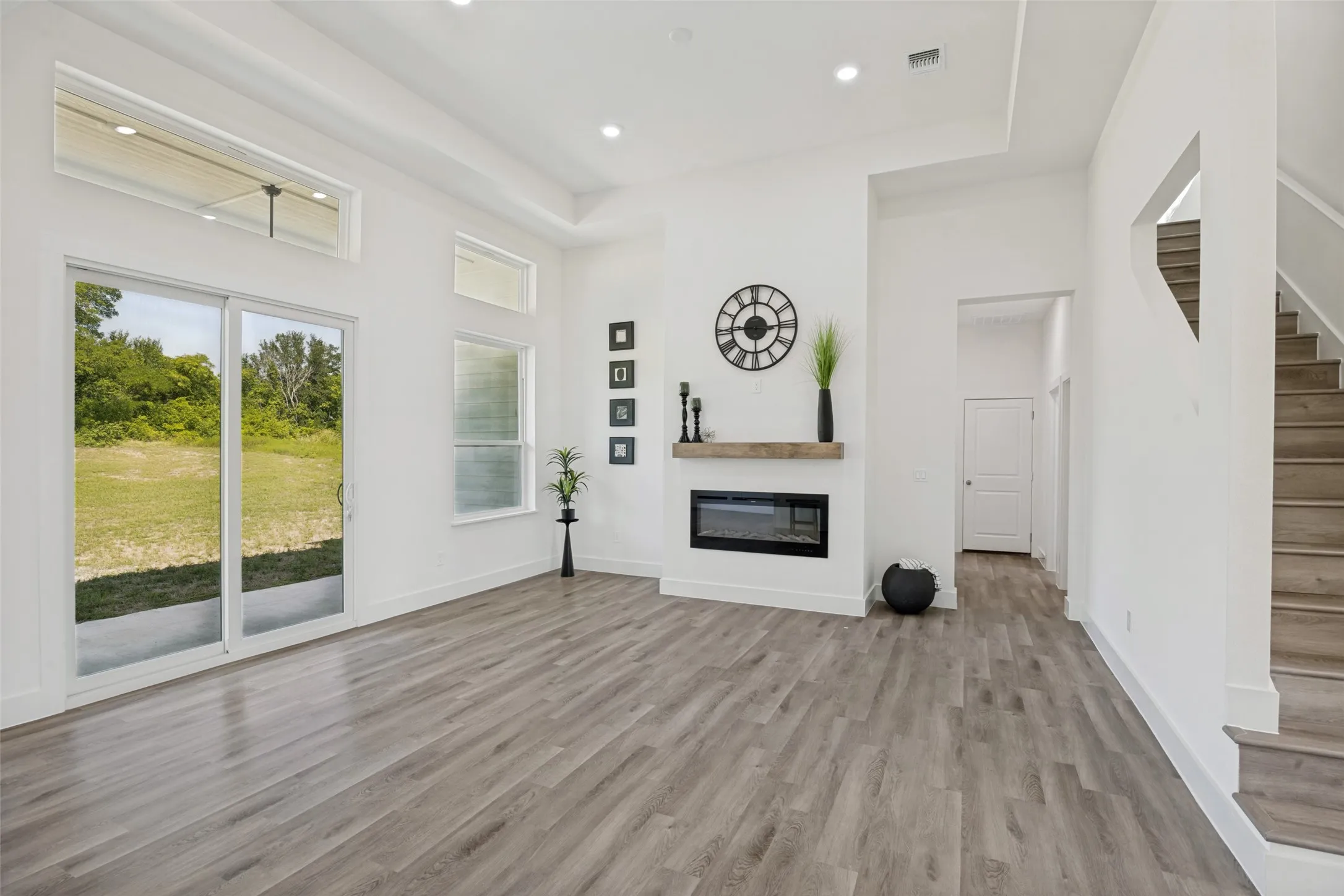 Living area featuring high ceilings, wood-finish flooring, and a modern fireplace with a wood mantle