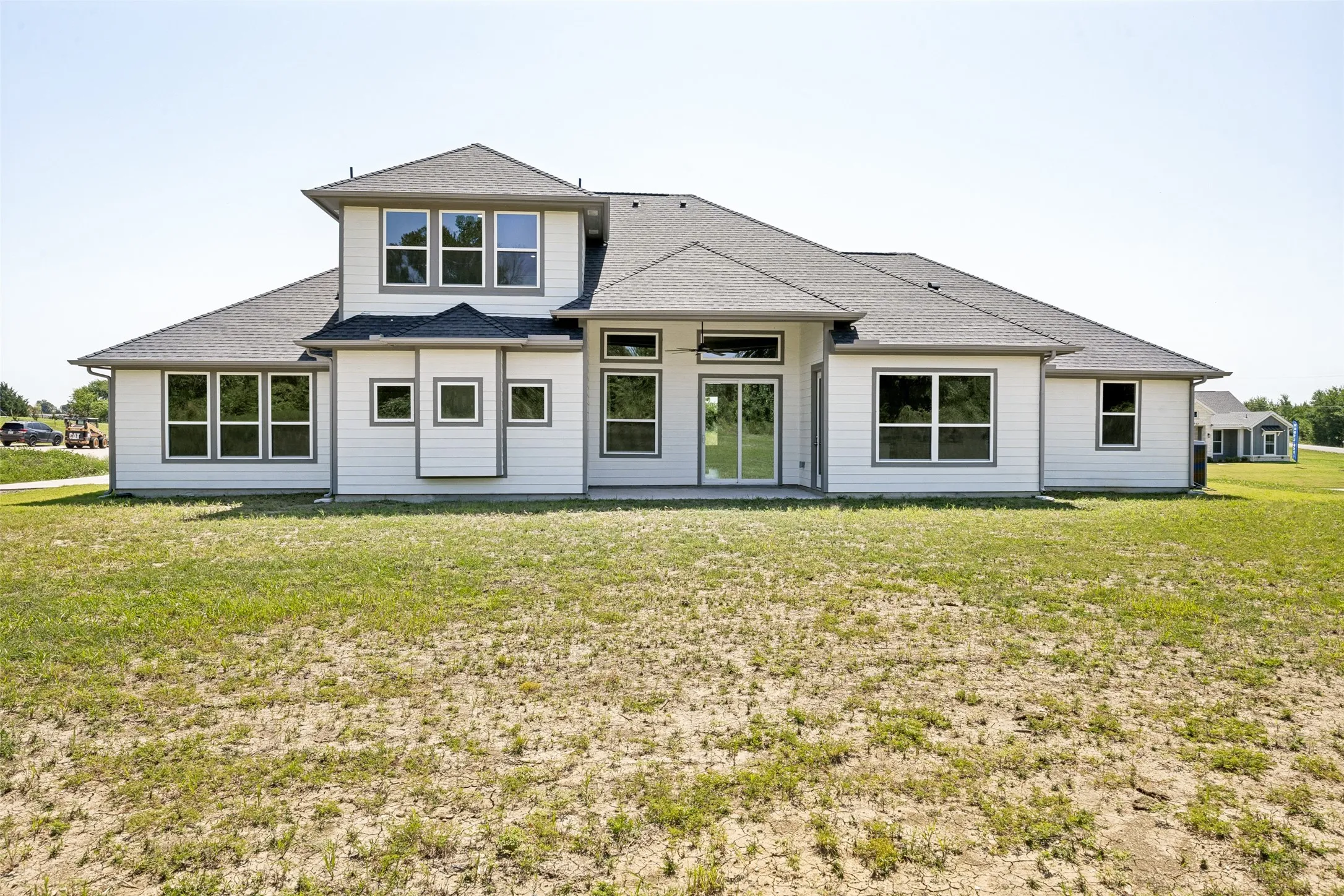 Contemporary rear exterior featuring white siding and multiple large windows