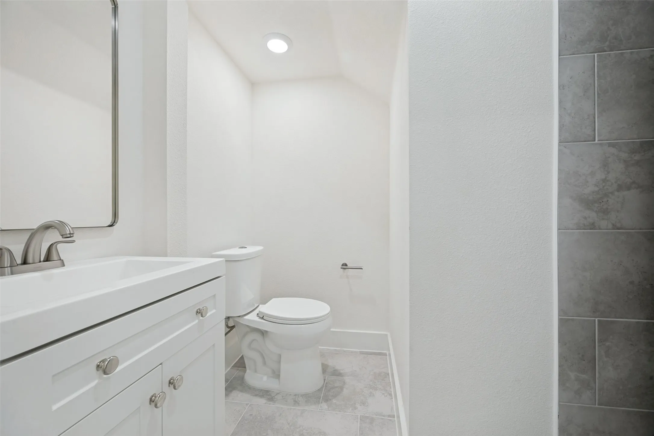 Modern bathroom featuring a white vanity with brushed nickel hardware, a rectangular undermount sink, and a matching brushed nickel faucet