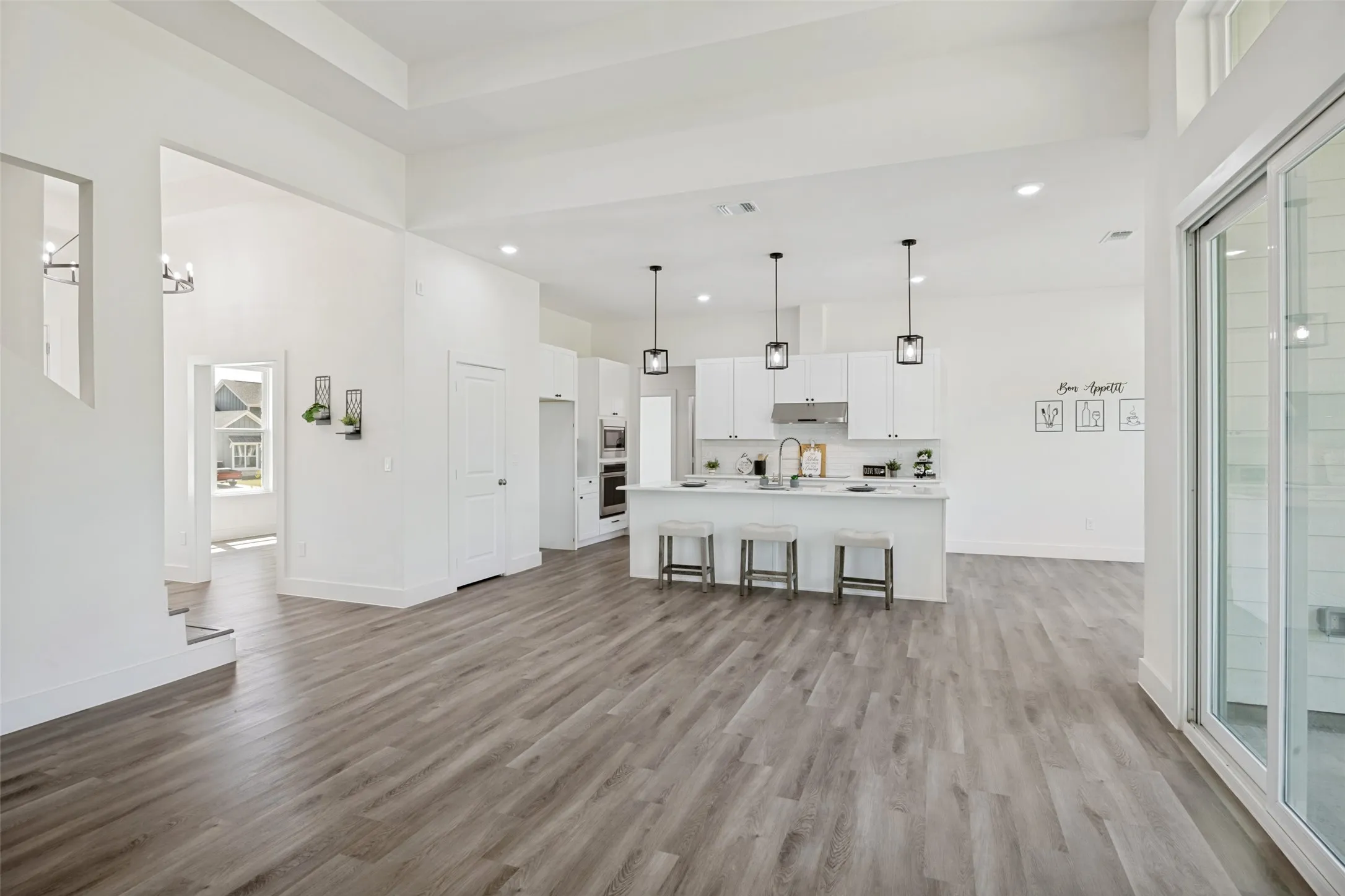 Spacious open-concept living area featuring wood-finish flooring, high ceilings, and recessed lighting
