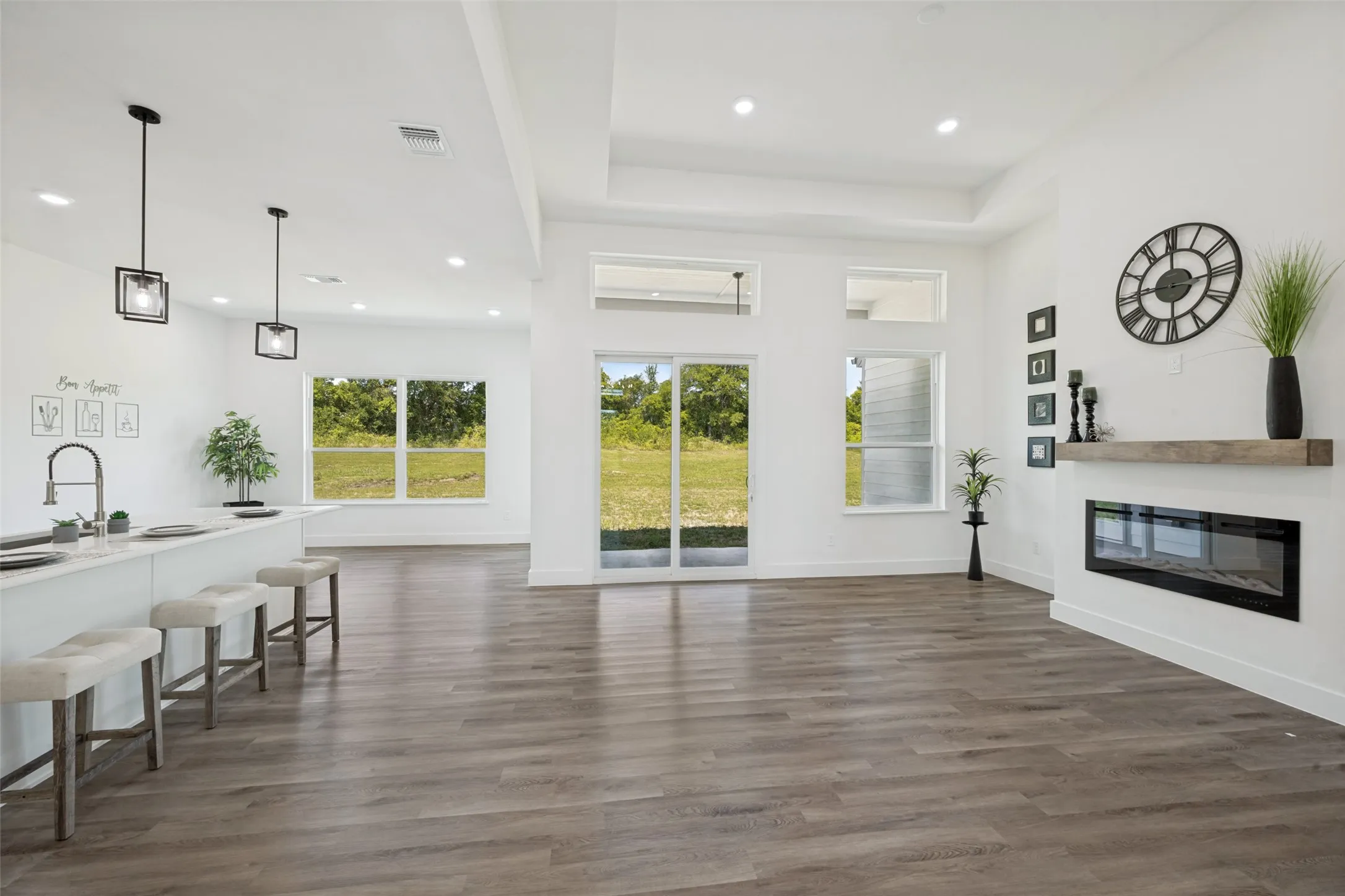 Spacious interior featuring wood-finish flooring, a contemporary linear fireplace with a wood mantel, and large windows