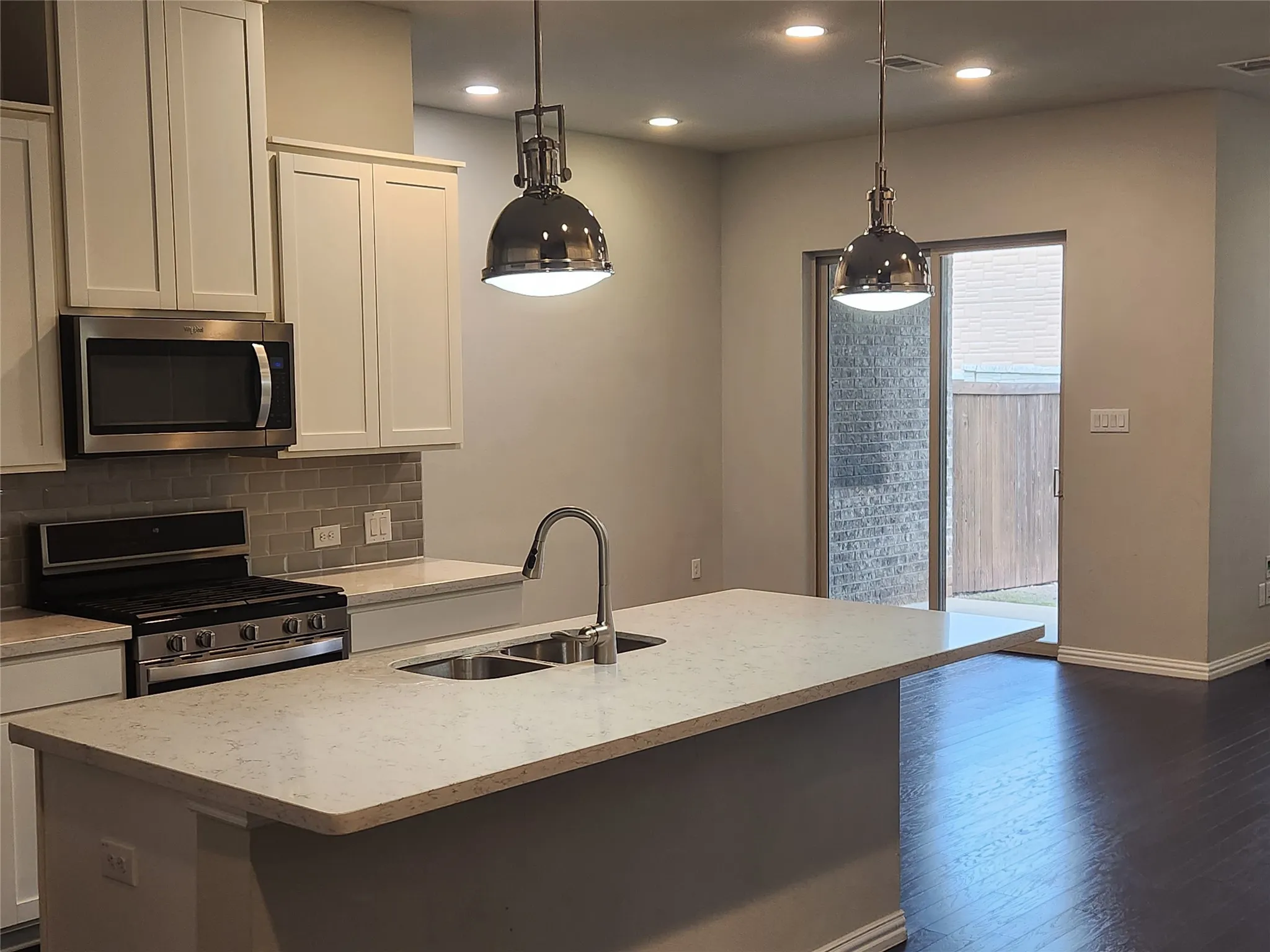Kitchen featuring a double basin stainless steel sink, a stainless steel gas range, and a built-in stainless steel microwave