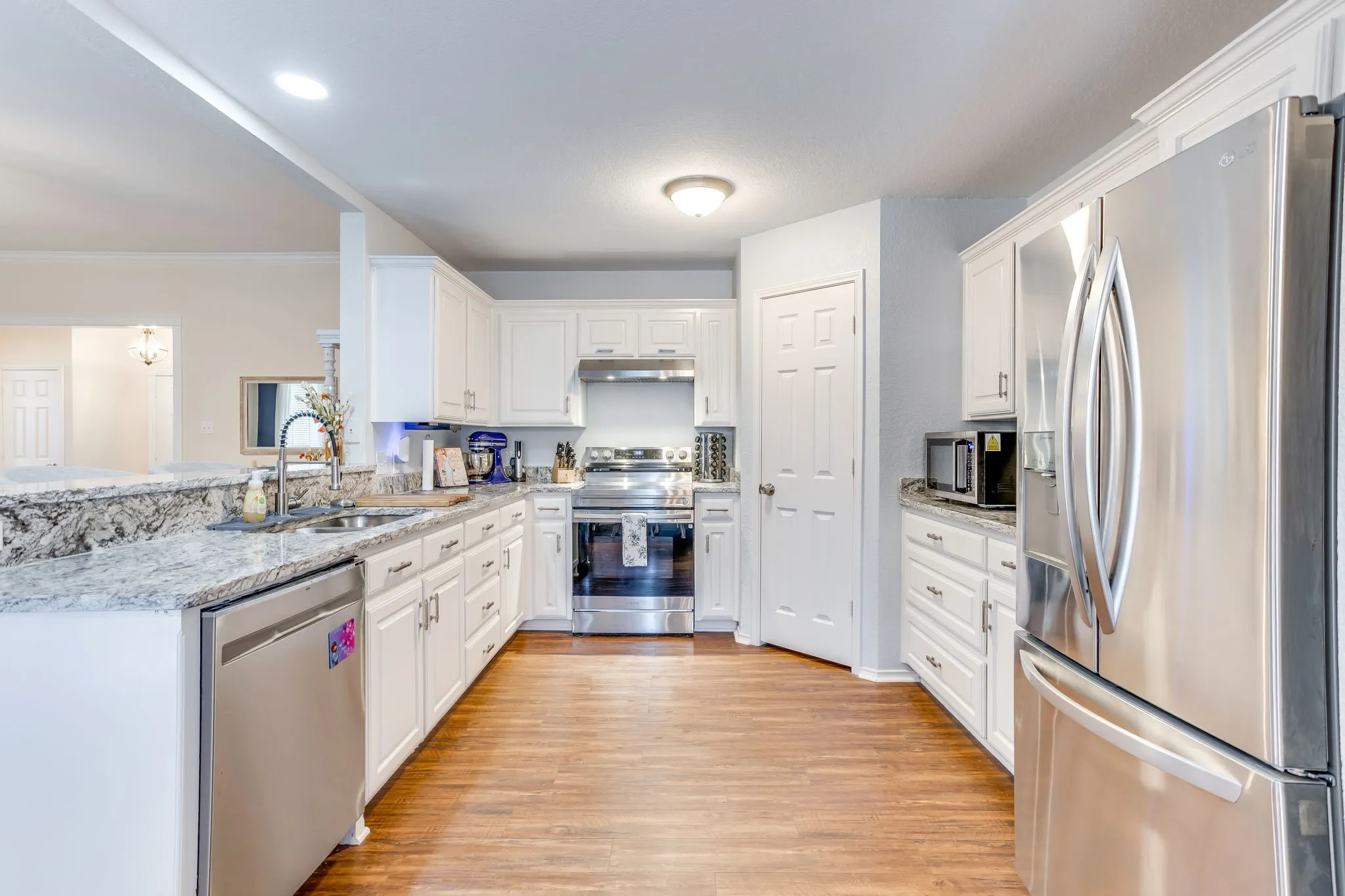 Kitchen featuring galley-style layout, slim, elongated brushed nickel bar pulls on the cabinets, and clean, eased edge profile on the countertops.