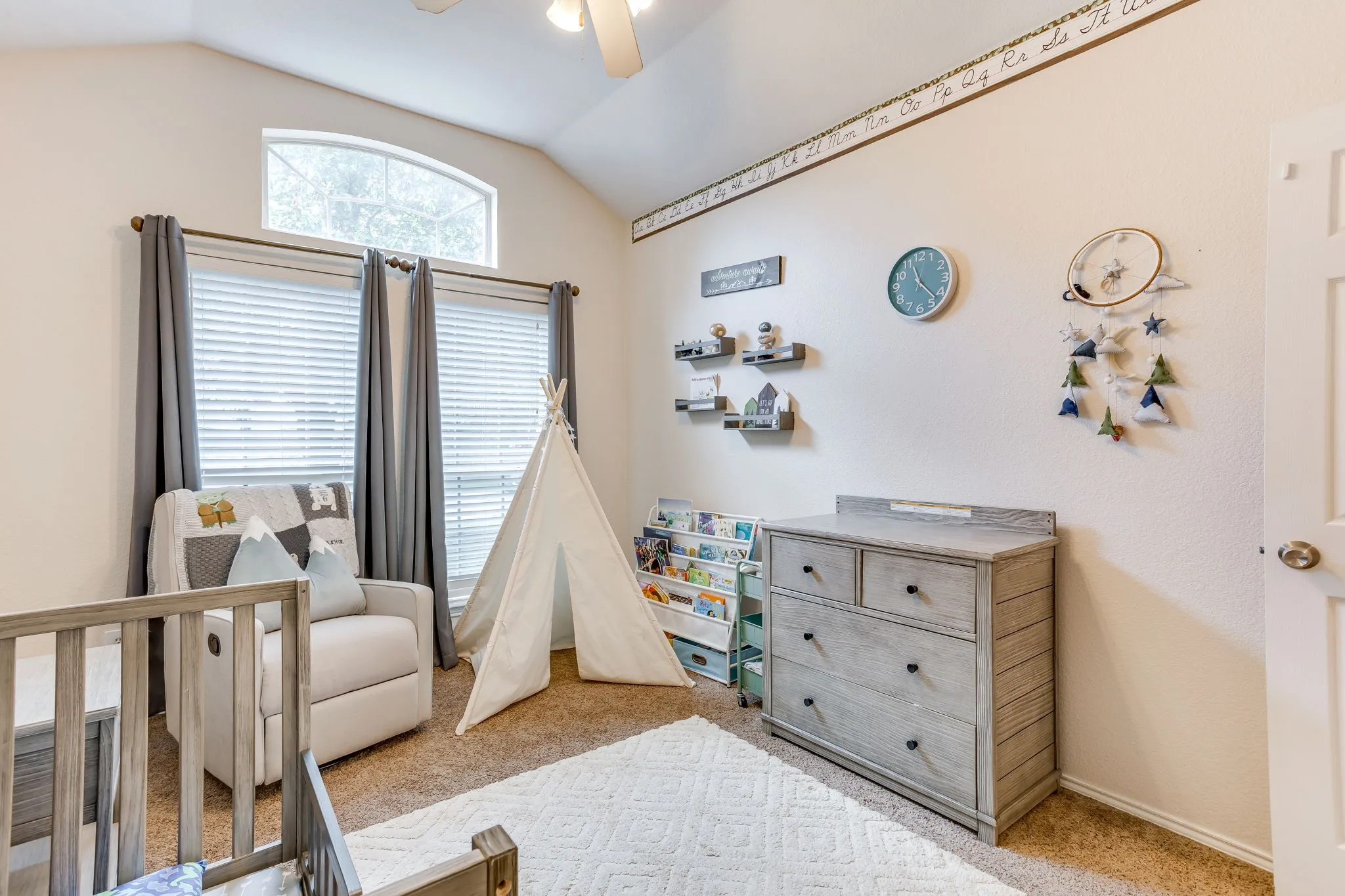Bedroom featuring two large vertical windows and a transom window for additional natural light, and a central multi-blade ceiling fan with polished metallic base, and frosted glass light shades.