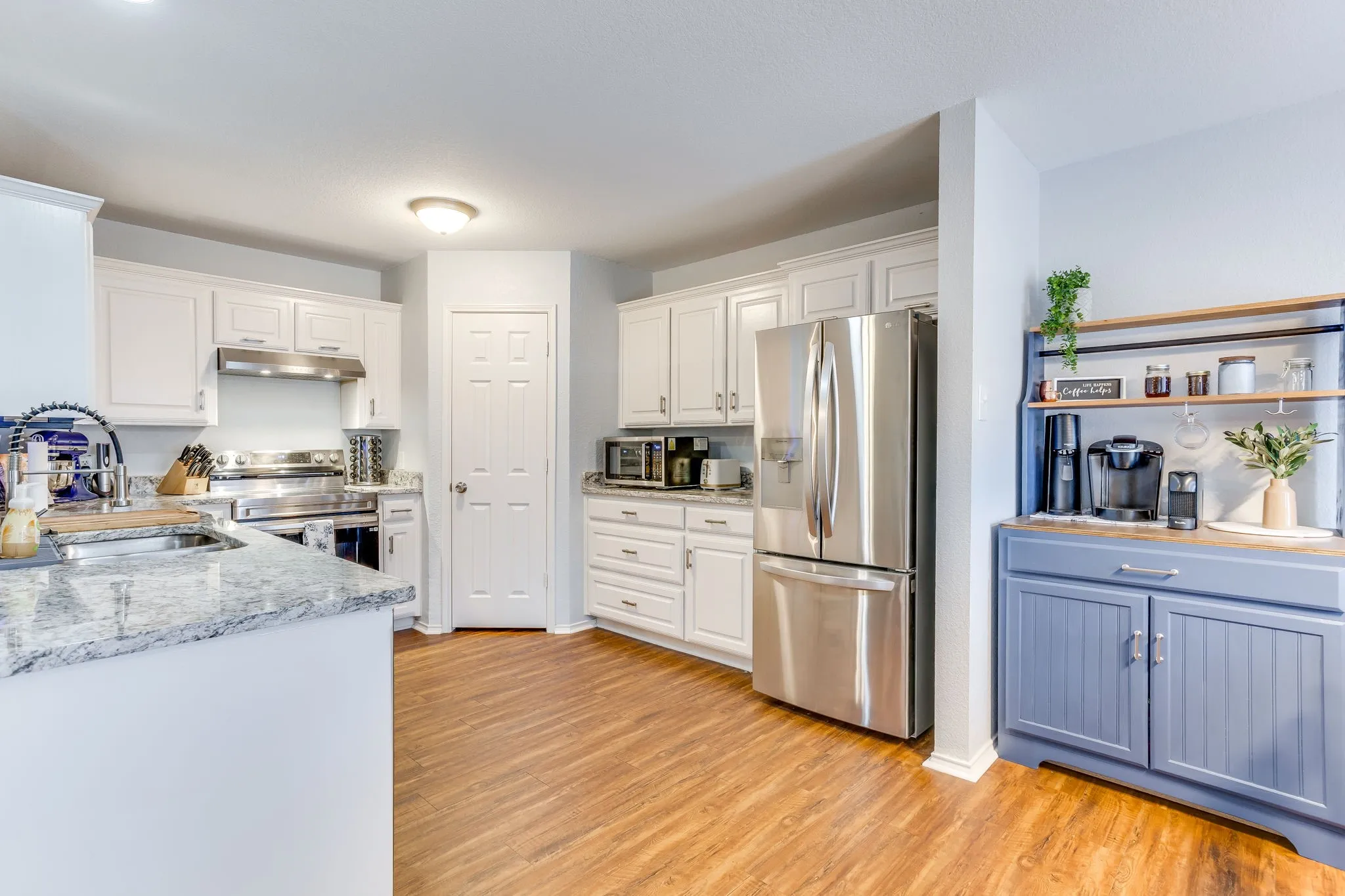 Kitchen featuring bright white shaker-style cabinets countertops with a high-contrast grey, white and black veining pattern,  and stainless steel appliances.