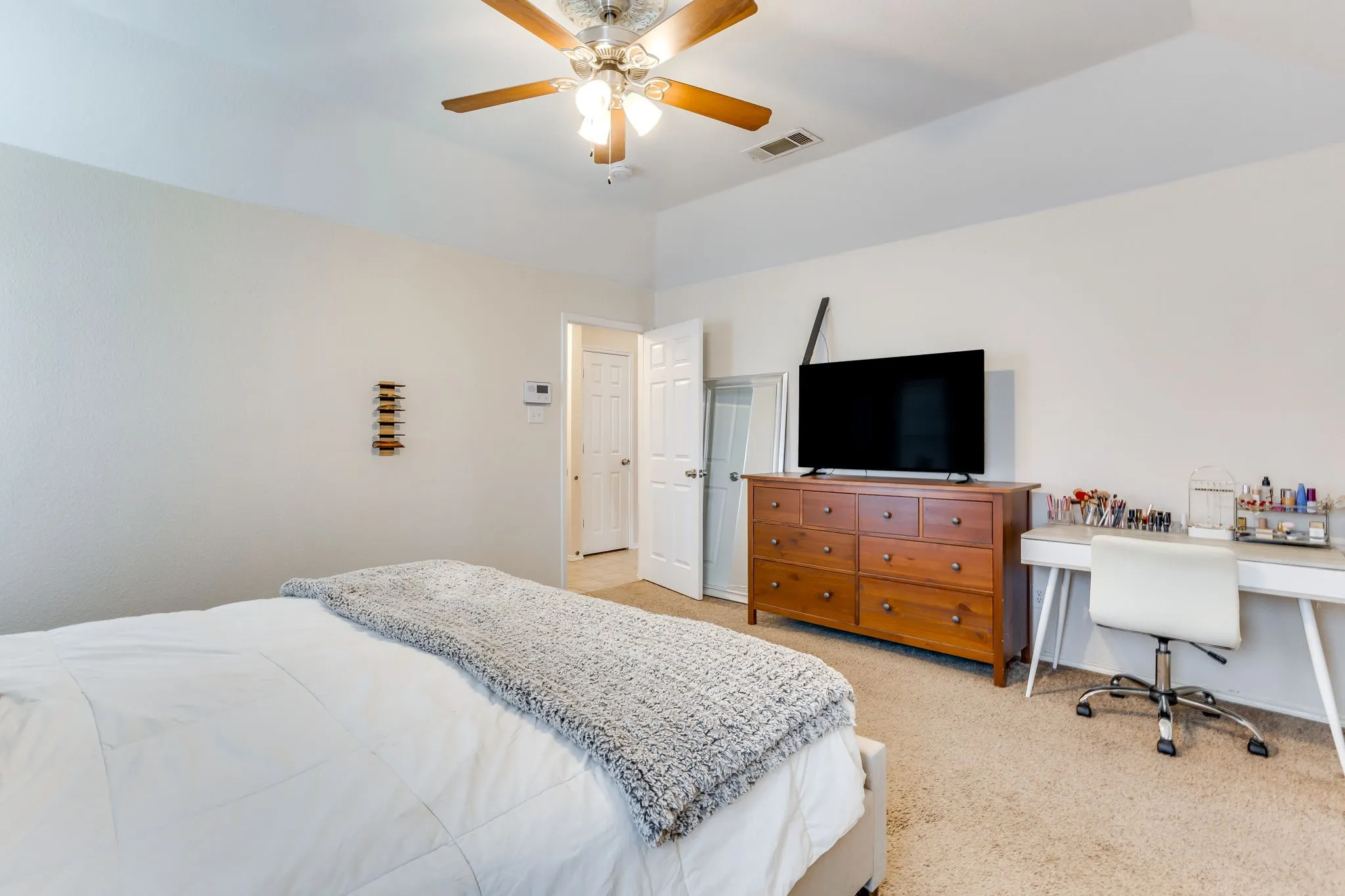 Primary bedroom featuring neutral colored wall to wall carpet and white, traditional six-panel interior door.