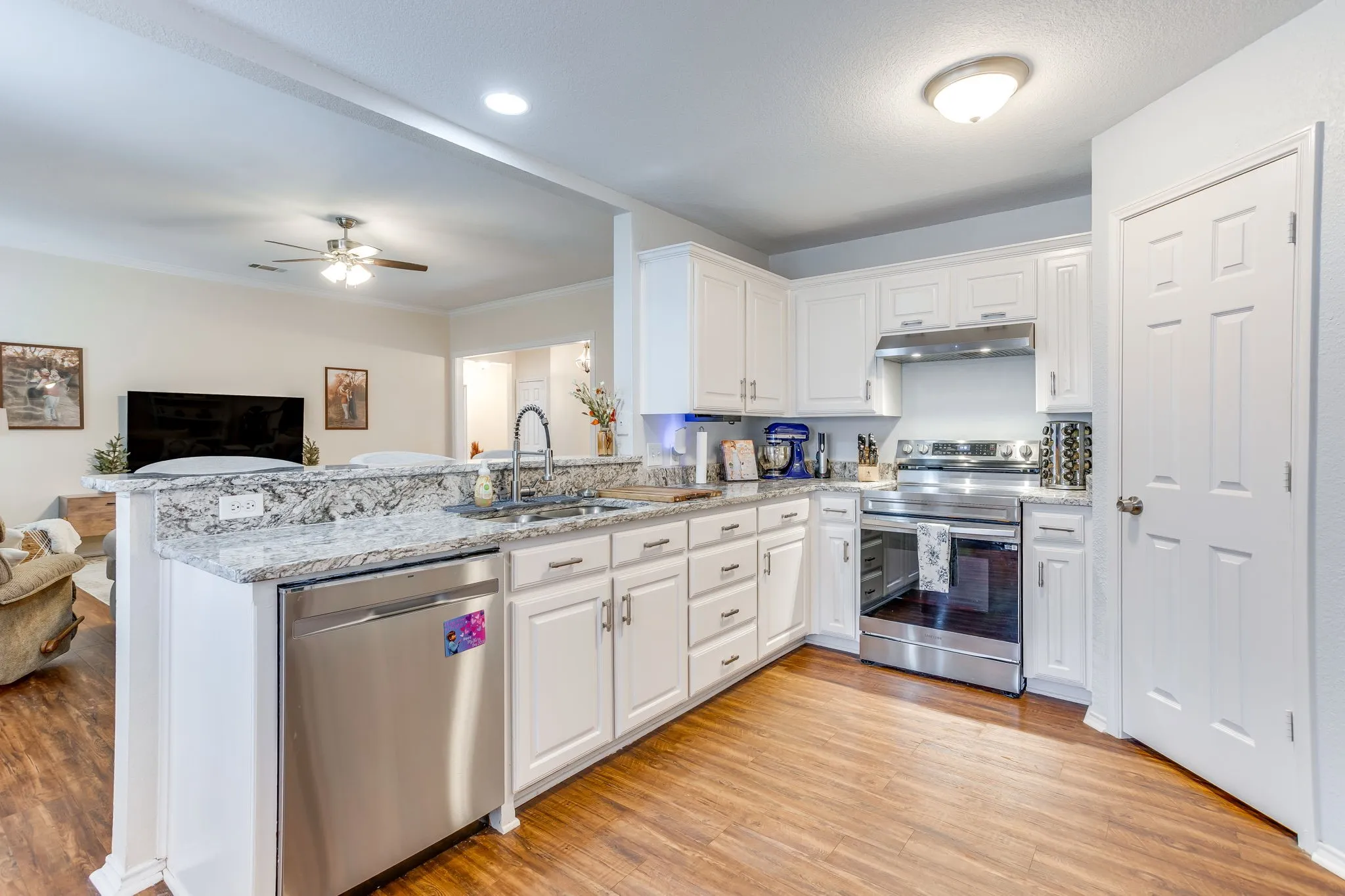  Kitchen featuring granite countertops with grey, charcoal and black veining, matching stainless steel appliances including a smooth-top electric range with matching overhead vent hood.