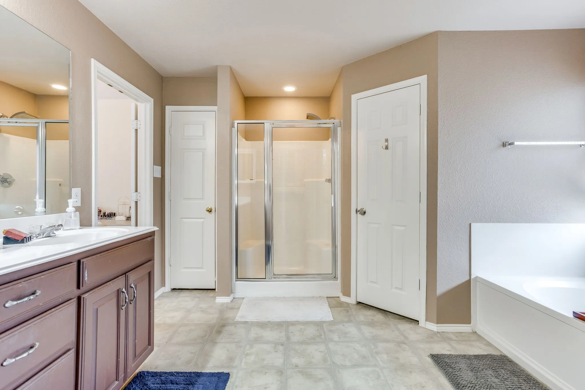 Primary bathroom featuring white painted baseboards, door frames, and classic 6-panel interior doors leading to linen closet and water closet, framed glass shower door with metallic trim.