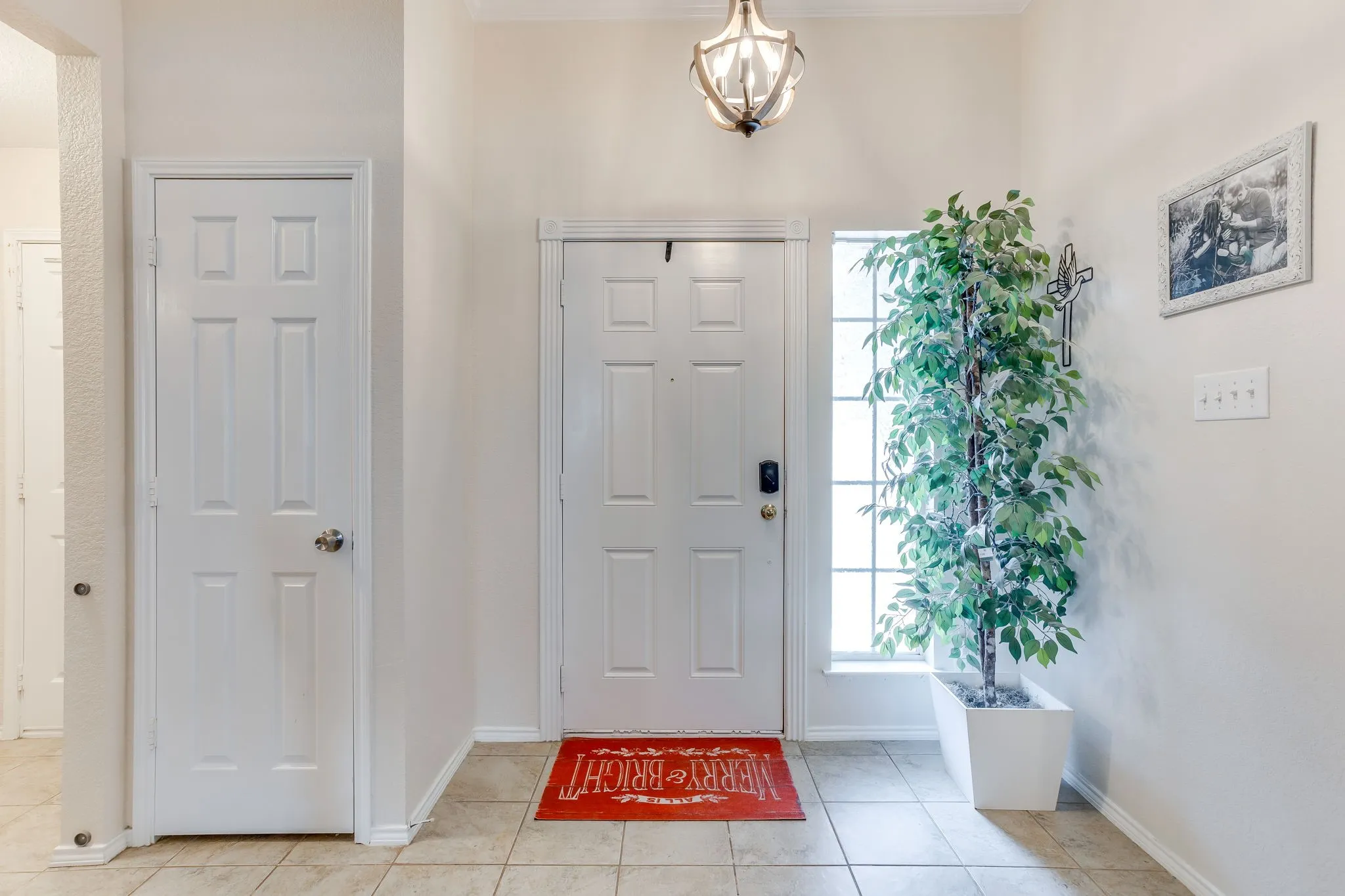 Entryway featuring a traditional 6-panel entry door, large-format ceramic tiles with a neutral beige, and a tiered geometric lantern chandelier hanging from the ceiling.