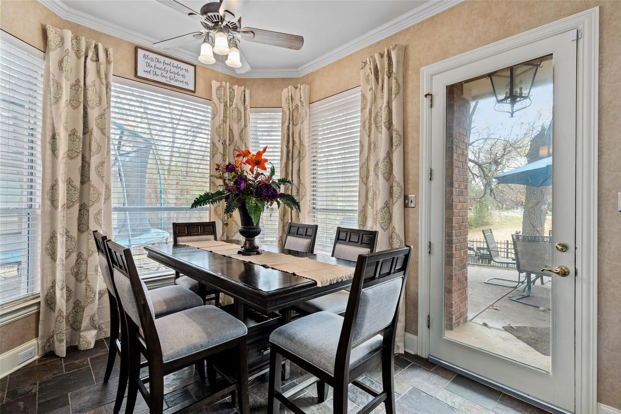Dining area featuring dark wood-finish flooring, textured wall covering, and a bay window with blinds