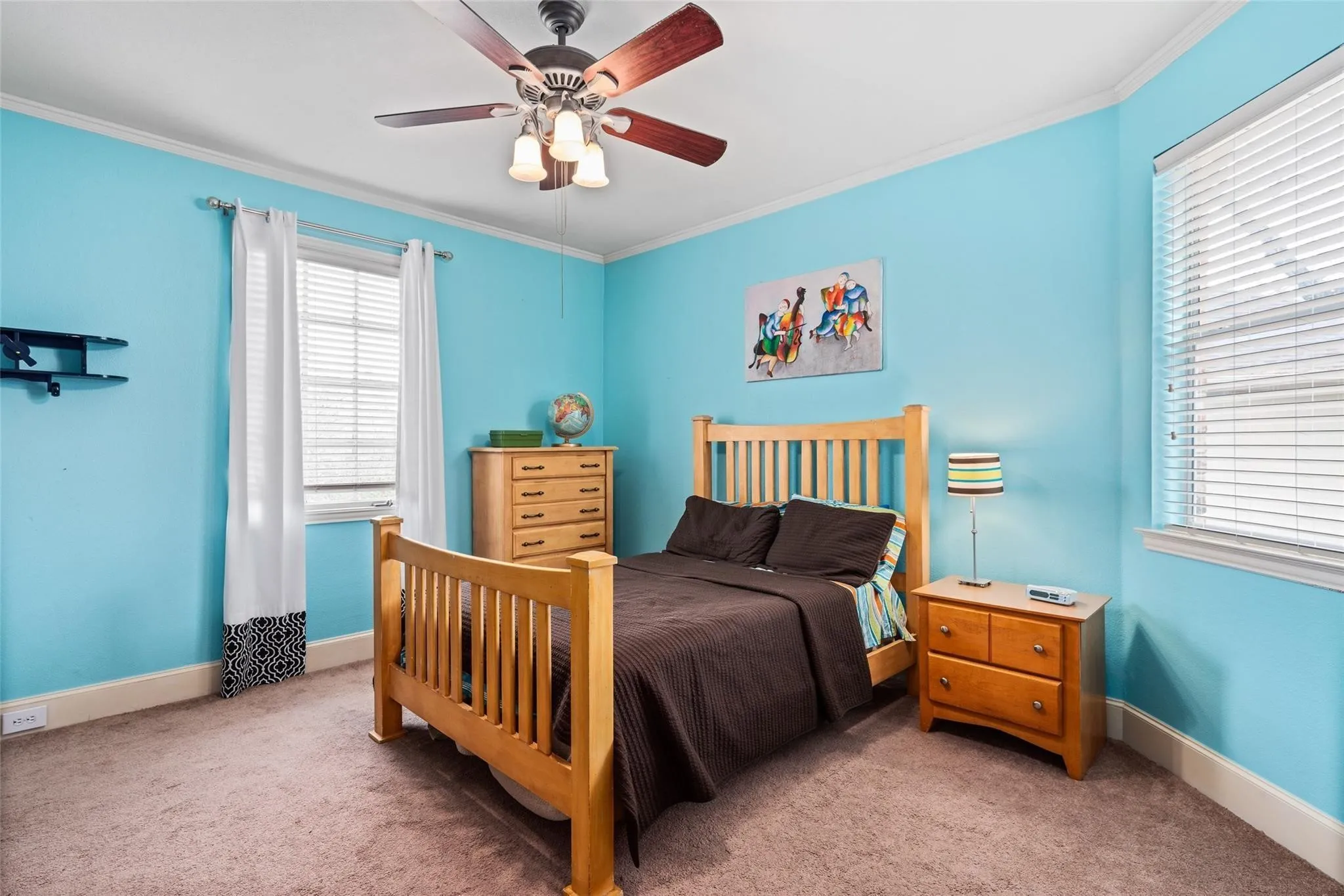 Bedroom featuring two windows with blinds, a ceiling fan with integrated lighting, crown molding, and carpet flooring