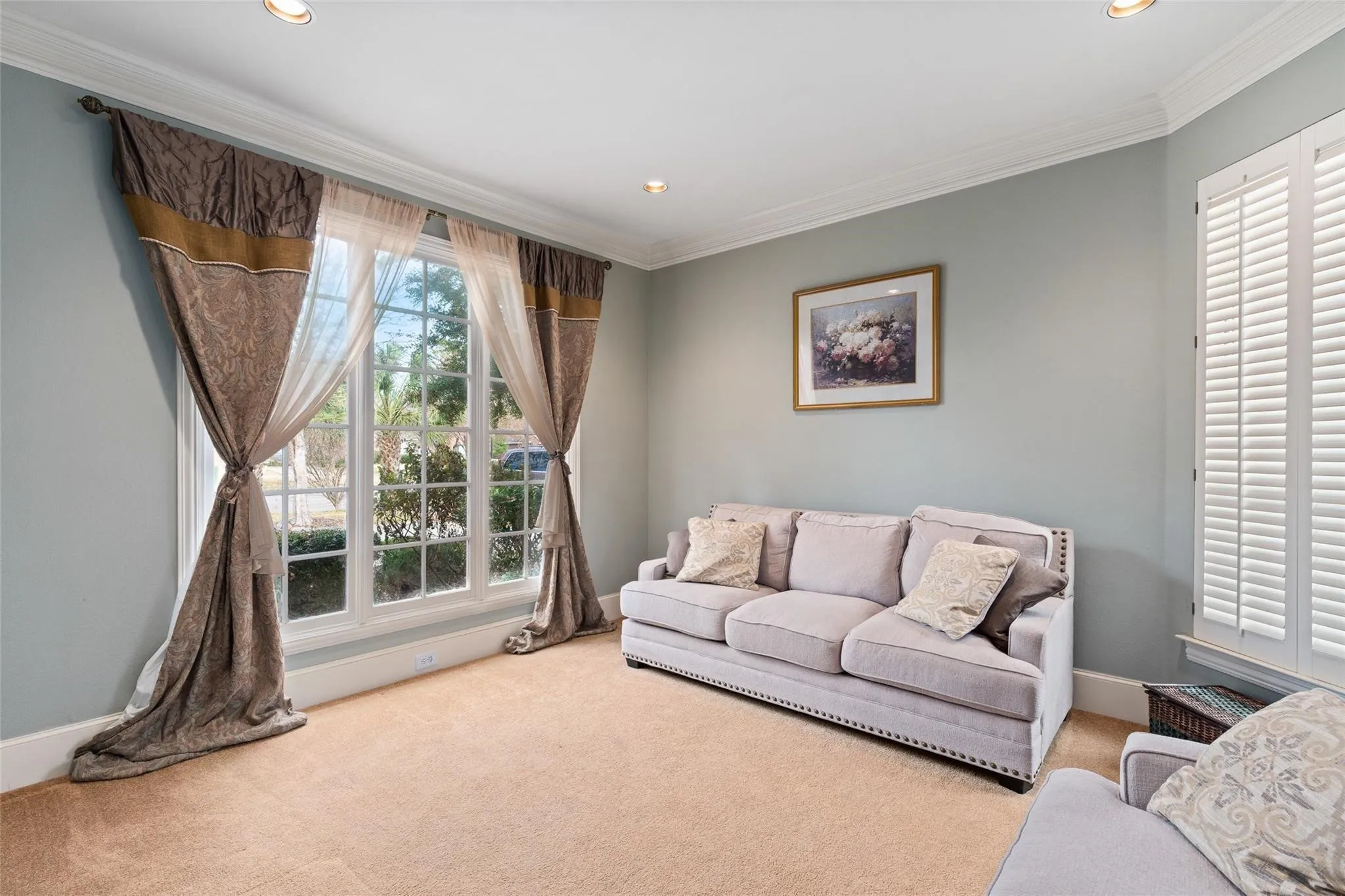 Recessed lighting illuminates a space featuring a large window with multiple panes and white plantation shutters