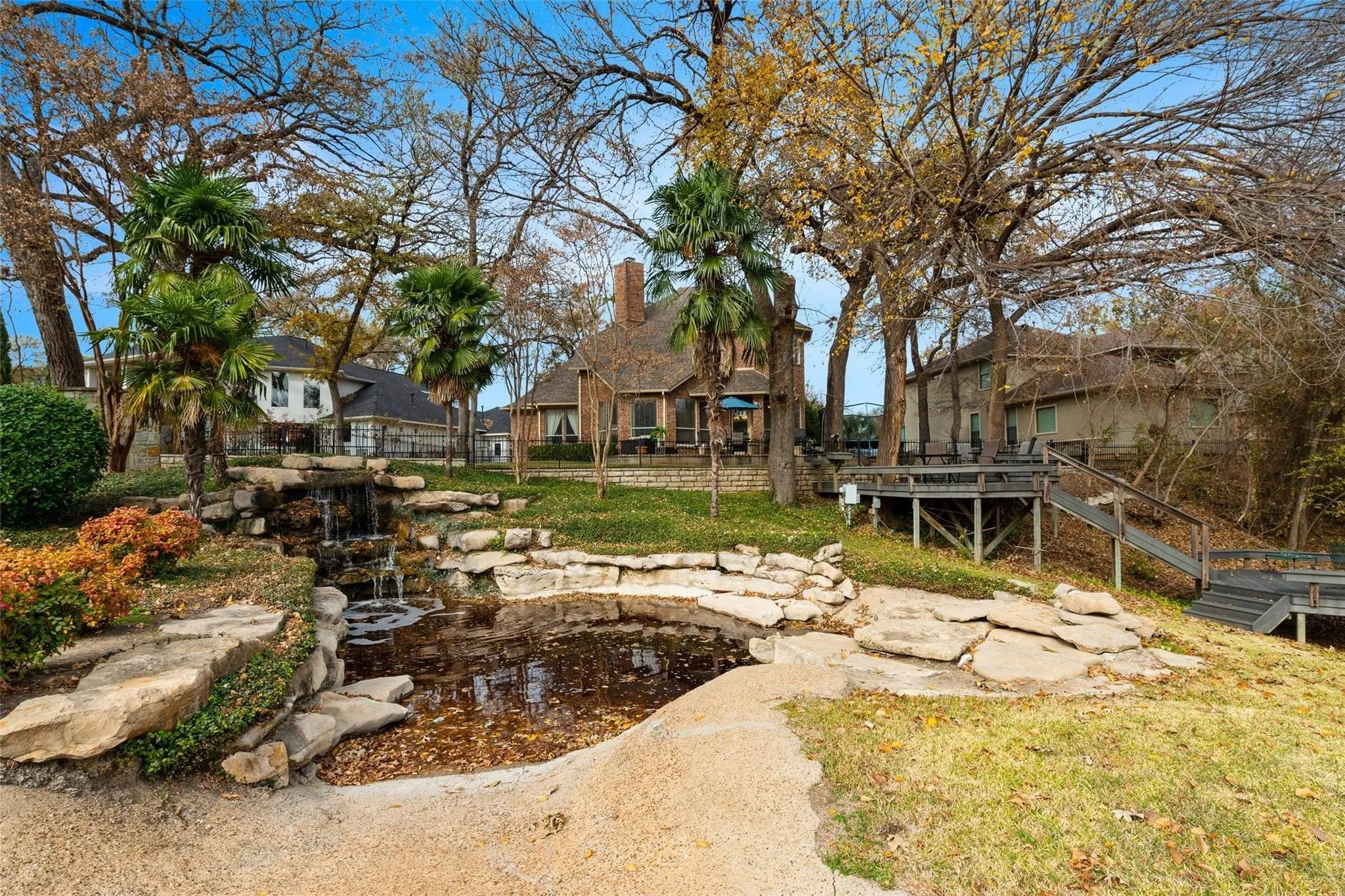Rear exterior featuring a multi-level deck, stone waterfall, and a natural pond