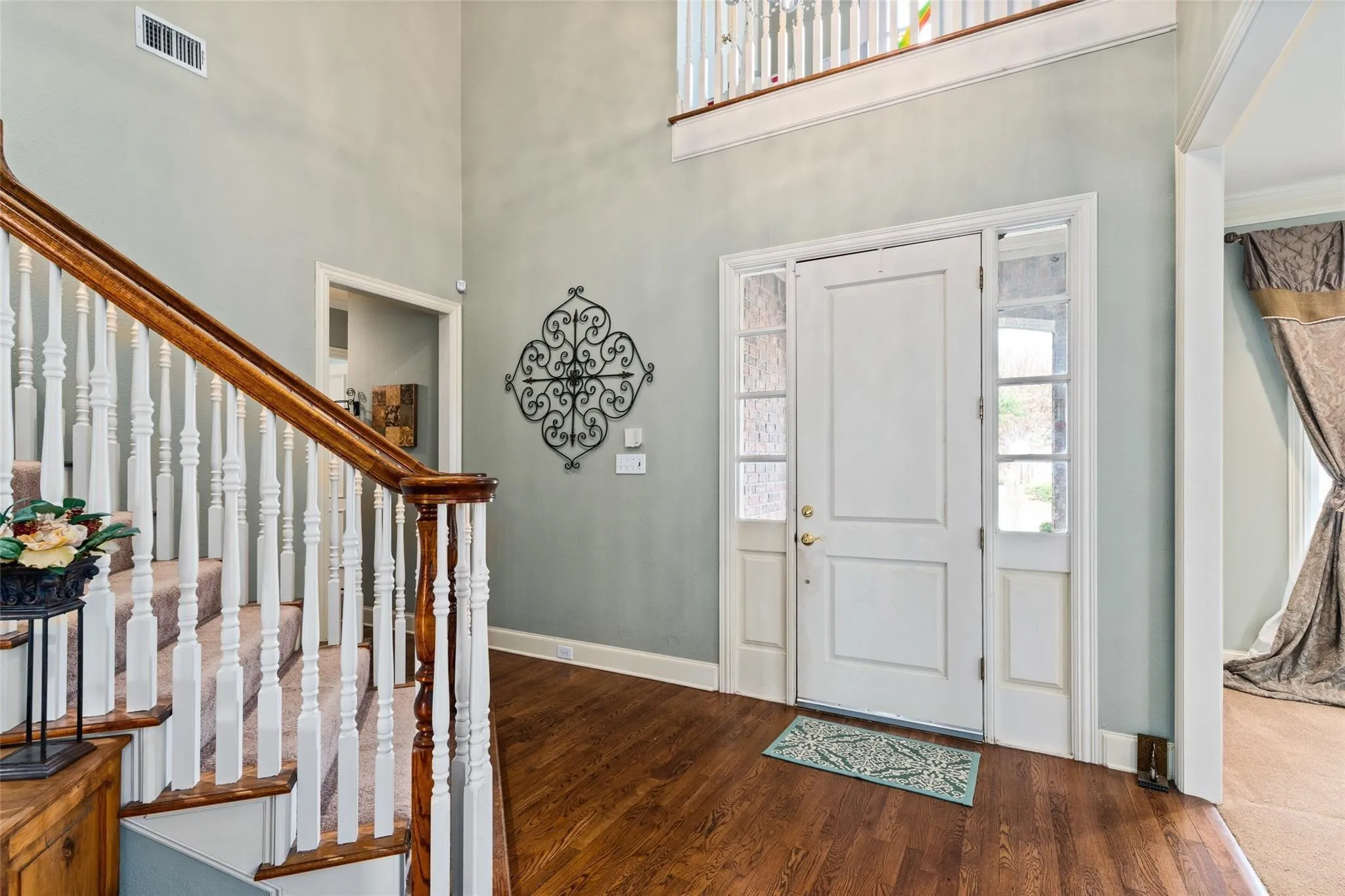 Grand foyer featuring a two-story ceiling, hardwood flooring, and a white paneled entry door with sidelights and transom windows