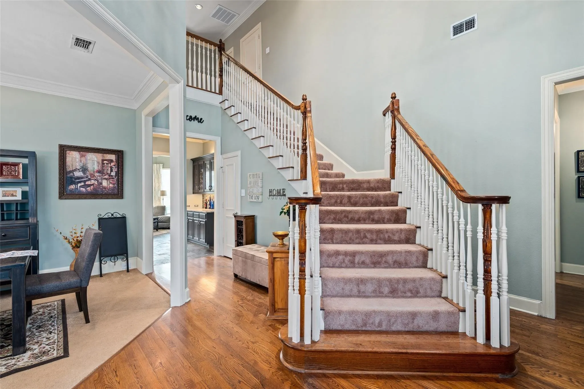 Grand staircase featuring wood-finish handrails and white balusters