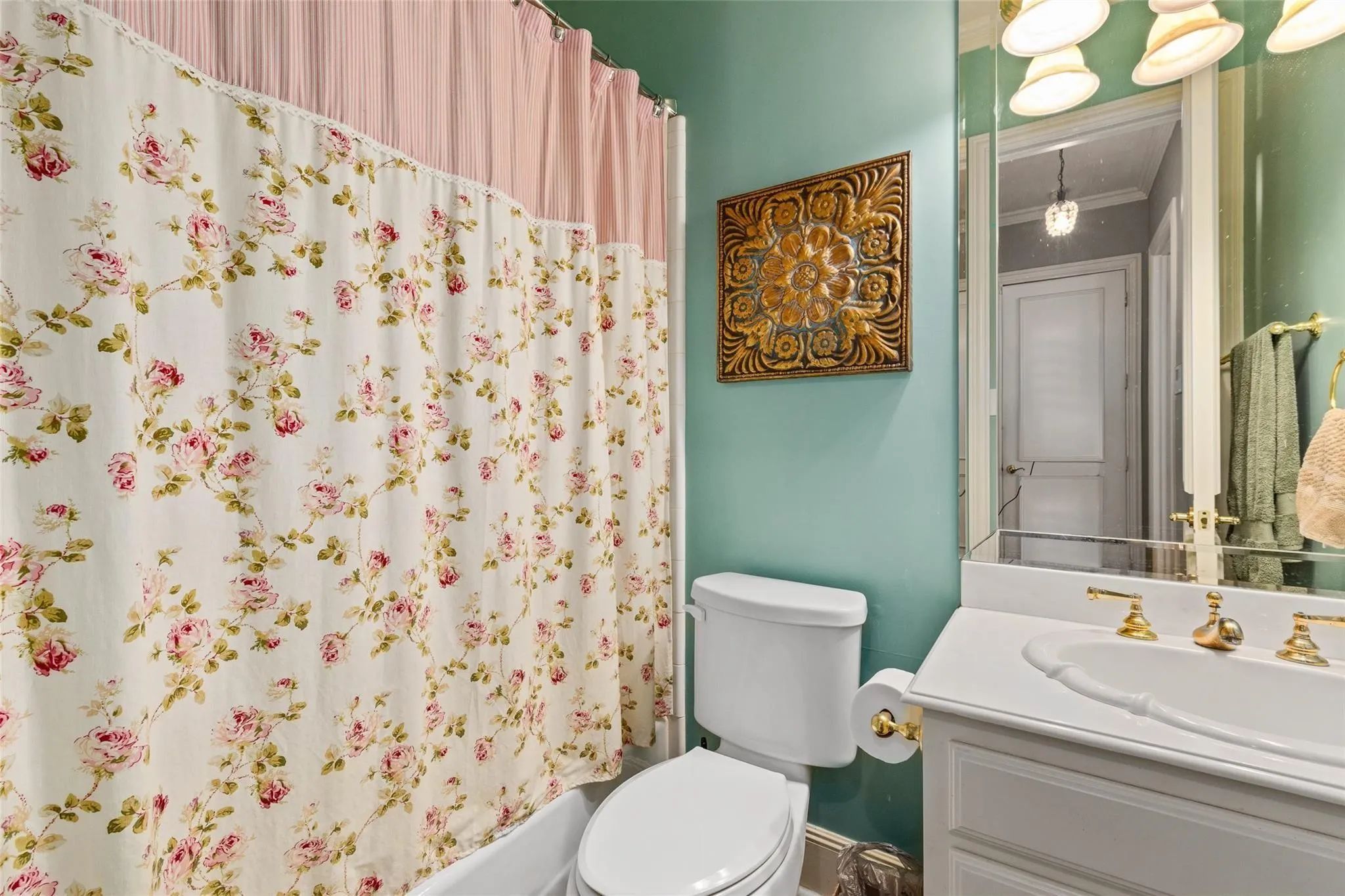 Bathroom featuring a white porcelain toilet, a white vanity with an integrated sink, gold-tone faucet hardware, and an overhead vanity light fixture