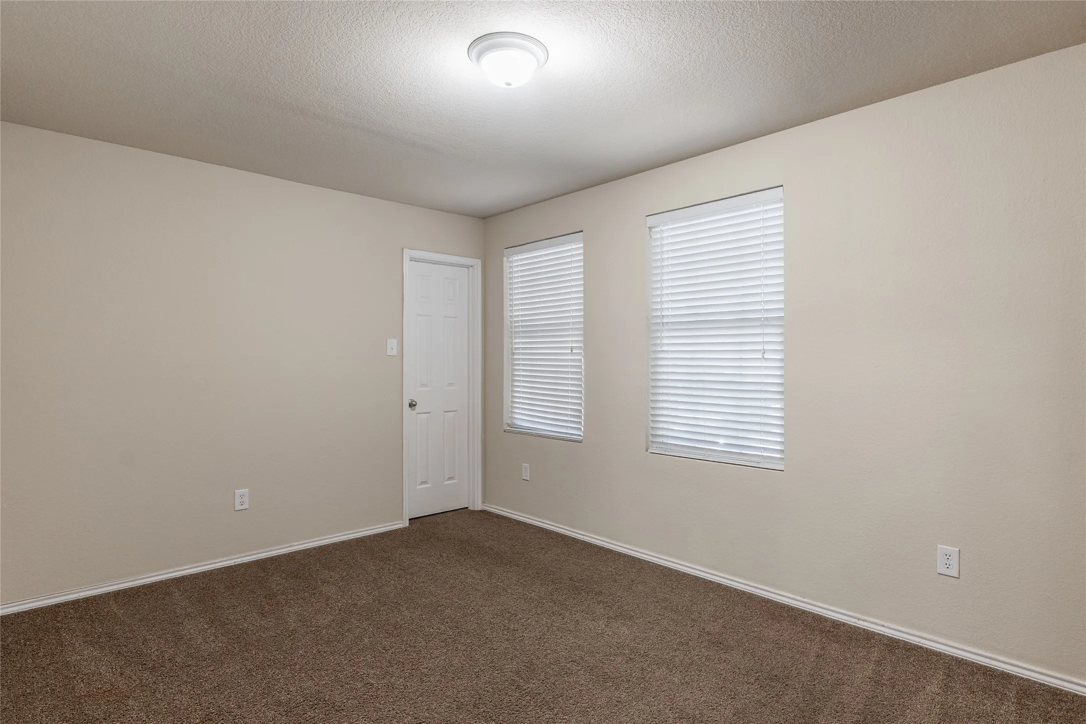 Neutral-toned walls complement the brown carpet flooring throughout this room