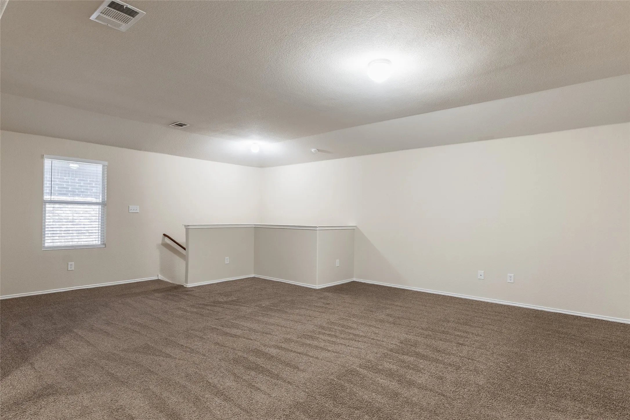Spacious carpeted room featuring light beige walls and white trim