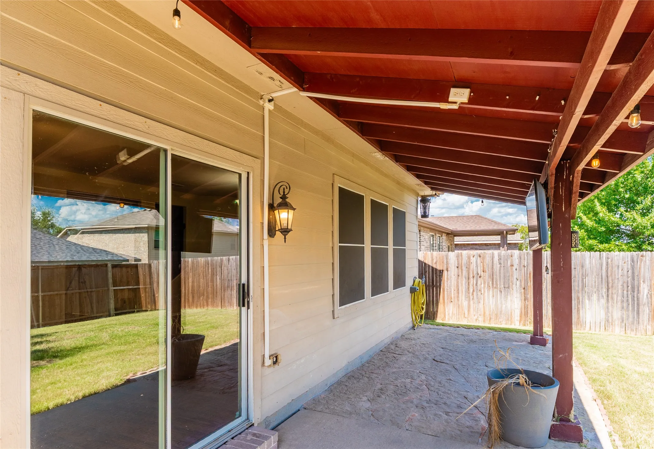 Covered patio featuring stamped concrete flooring, exposed wood beam ceiling, and overhead string lighting