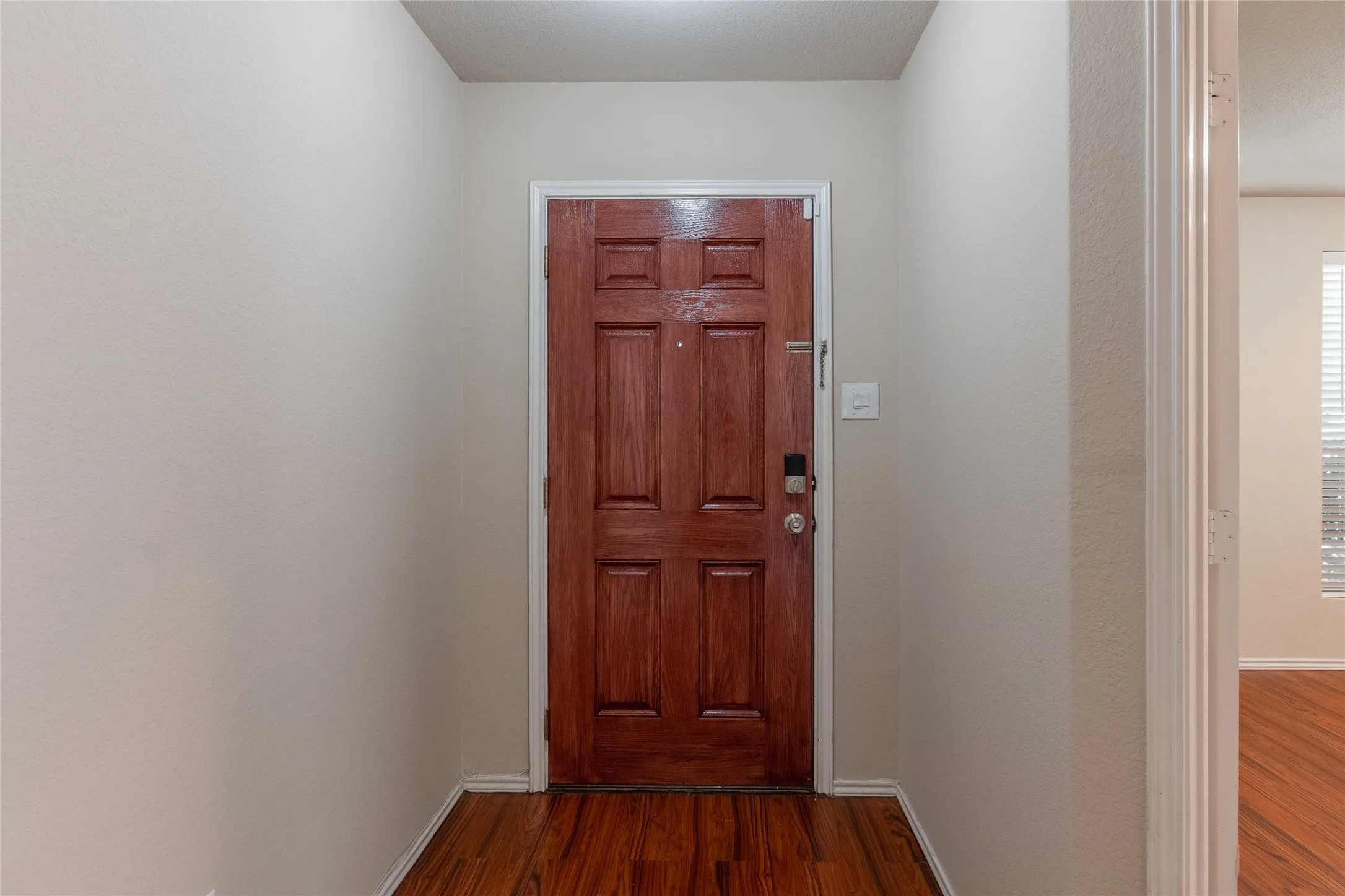 Warm wood-finish flooring complements the paneled wood entry door
