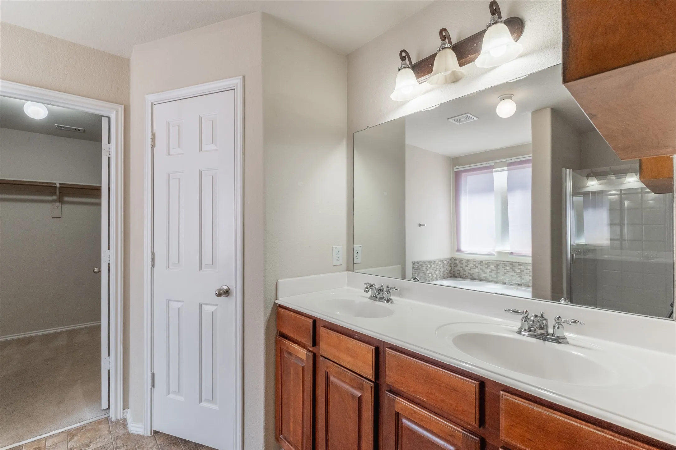 Dual vanity with white countertops, wood cabinetry, and a large mirror