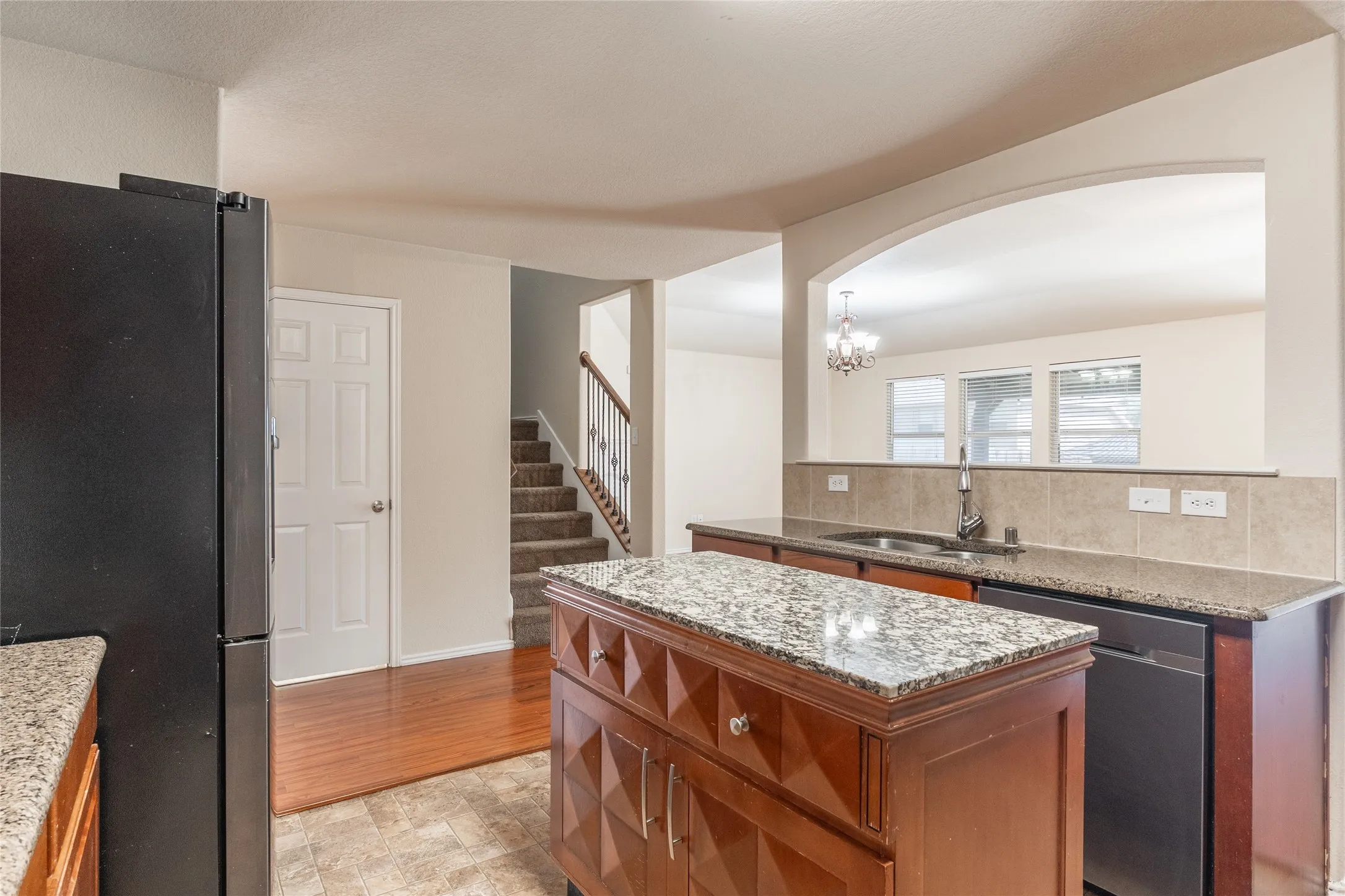 Kitchen featuring granite countertops, a built-in island with storage, dark wood-finish cabinetry, and a tile backsplash