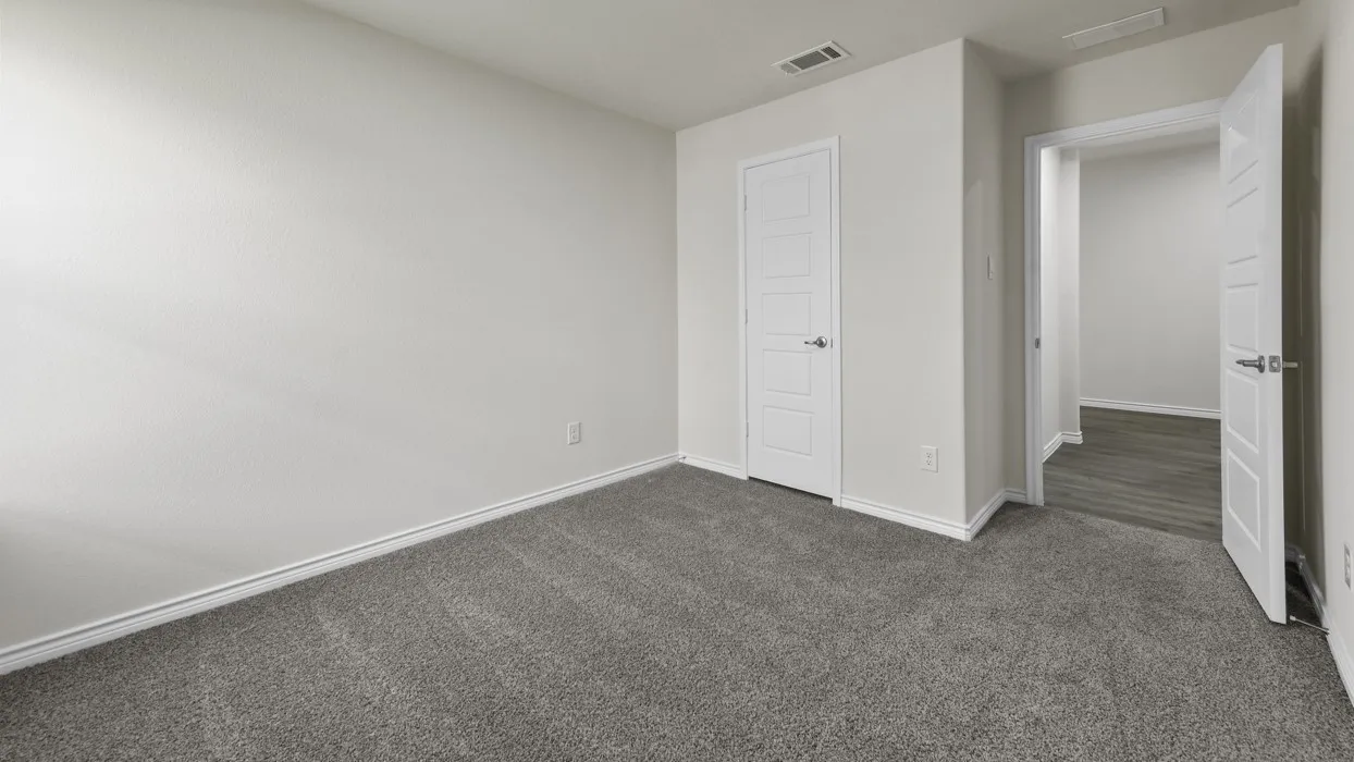 Spacious room featuring neutral carpeting, white baseboards, and a white interior door with contemporary hardware