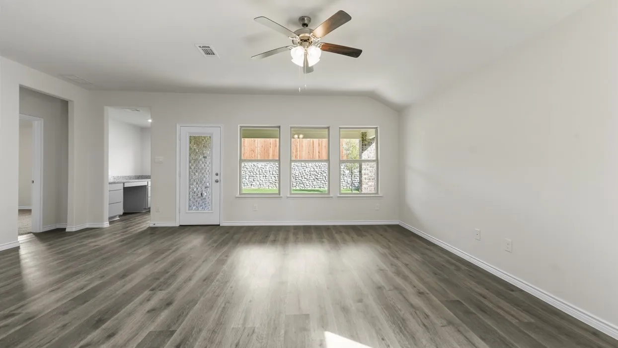 Spacious interior featuring wood-finish flooring, vaulted ceilings, and a ceiling fan with light fixture