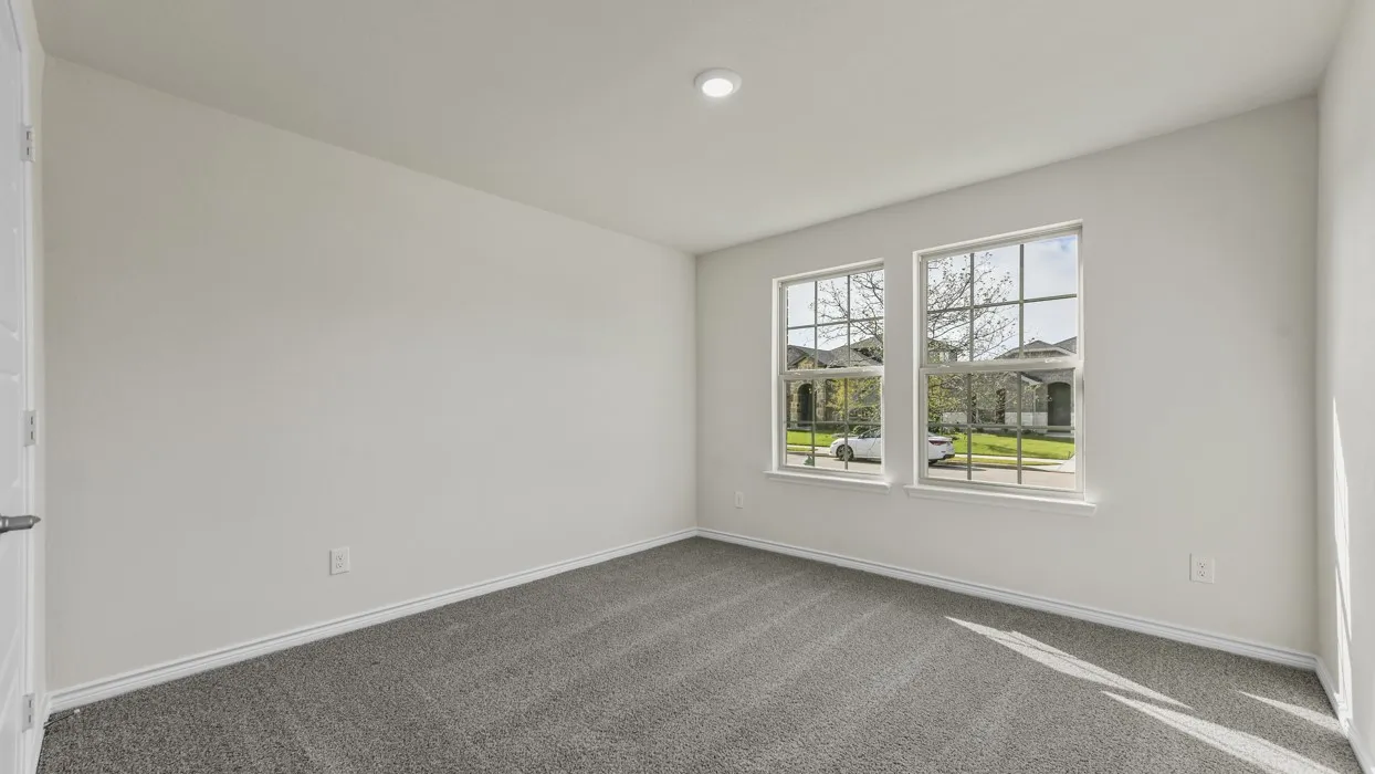 Spacious room featuring neutral paint, gray carpeting, a single recessed ceiling light, and two large windows with grid patterns