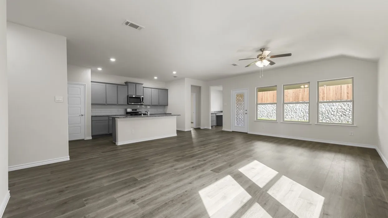 Spacious open-concept living area featuring wood-finish flooring, a contemporary kitchen with gray cabinetry, a breakfast bar, and stainless steel appliances
