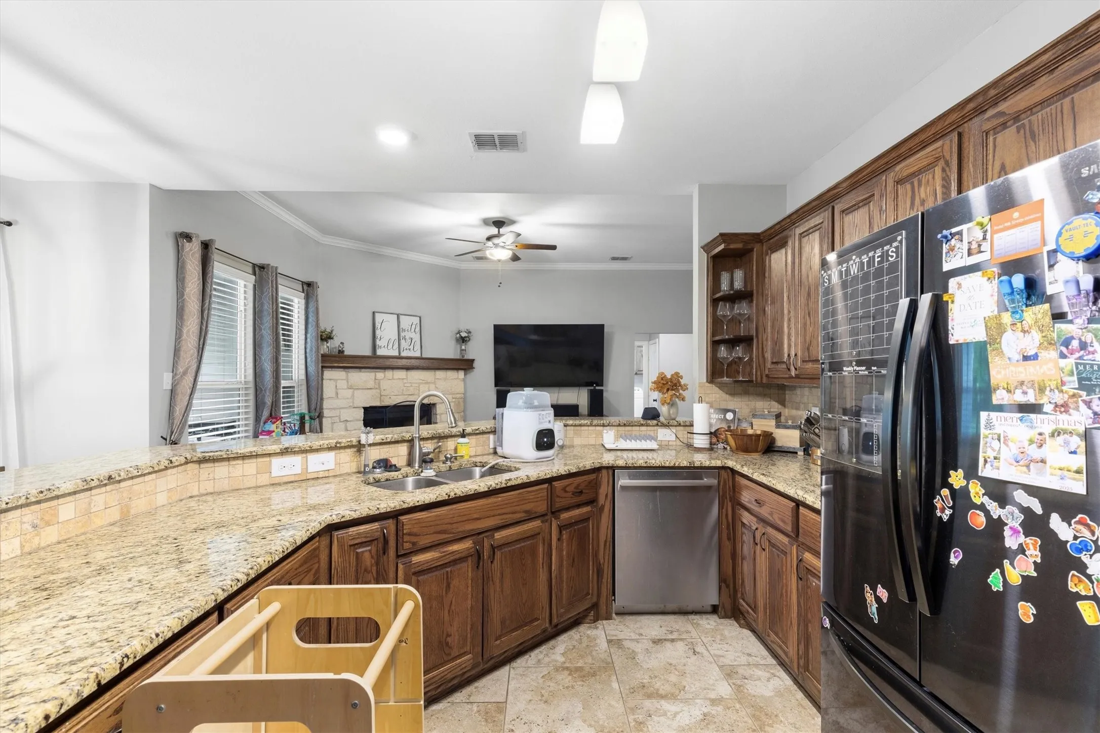Kitchen featuring wood cabinetry, granite countertops, tile flooring, and stainless steel appliances