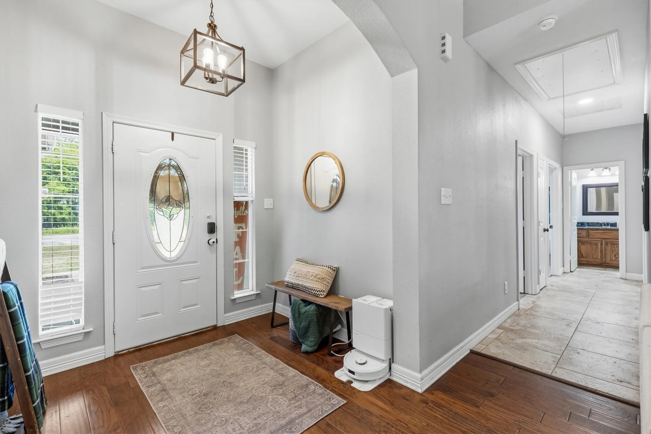 Entryway featuring a decorative glass front door with sidelight windows, vaulted ceiling, wood-finish flooring, and a hallway with tile flooring