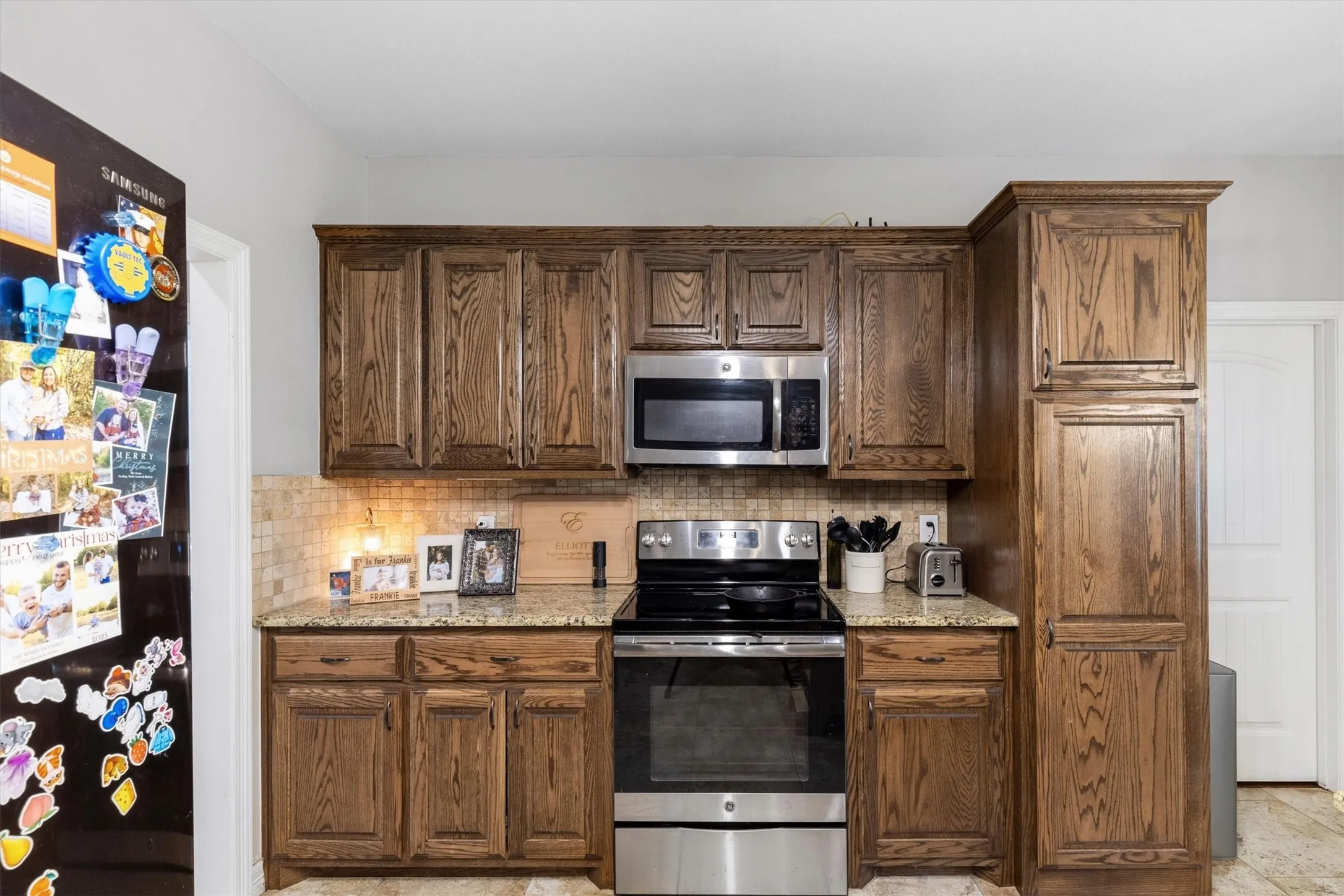 Kitchen featuring wood cabinetry, stainless steel appliances, granite countertops, and a tiled backsplash