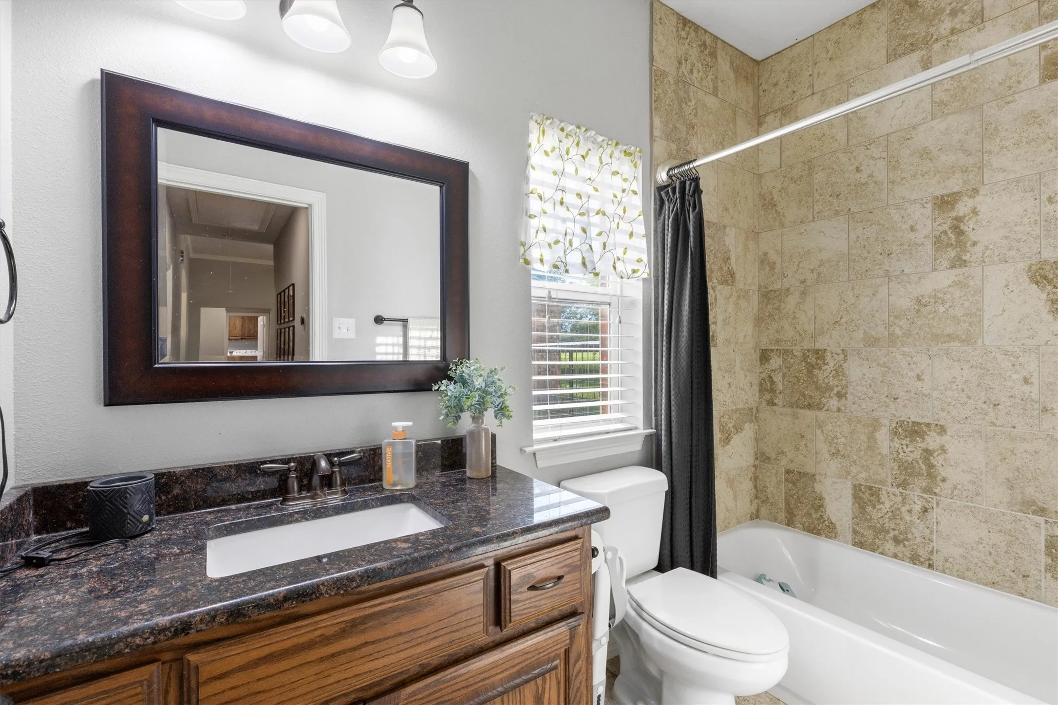 Bathroom featuring a wood-finish vanity with a dark speckled countertop and integrated sink