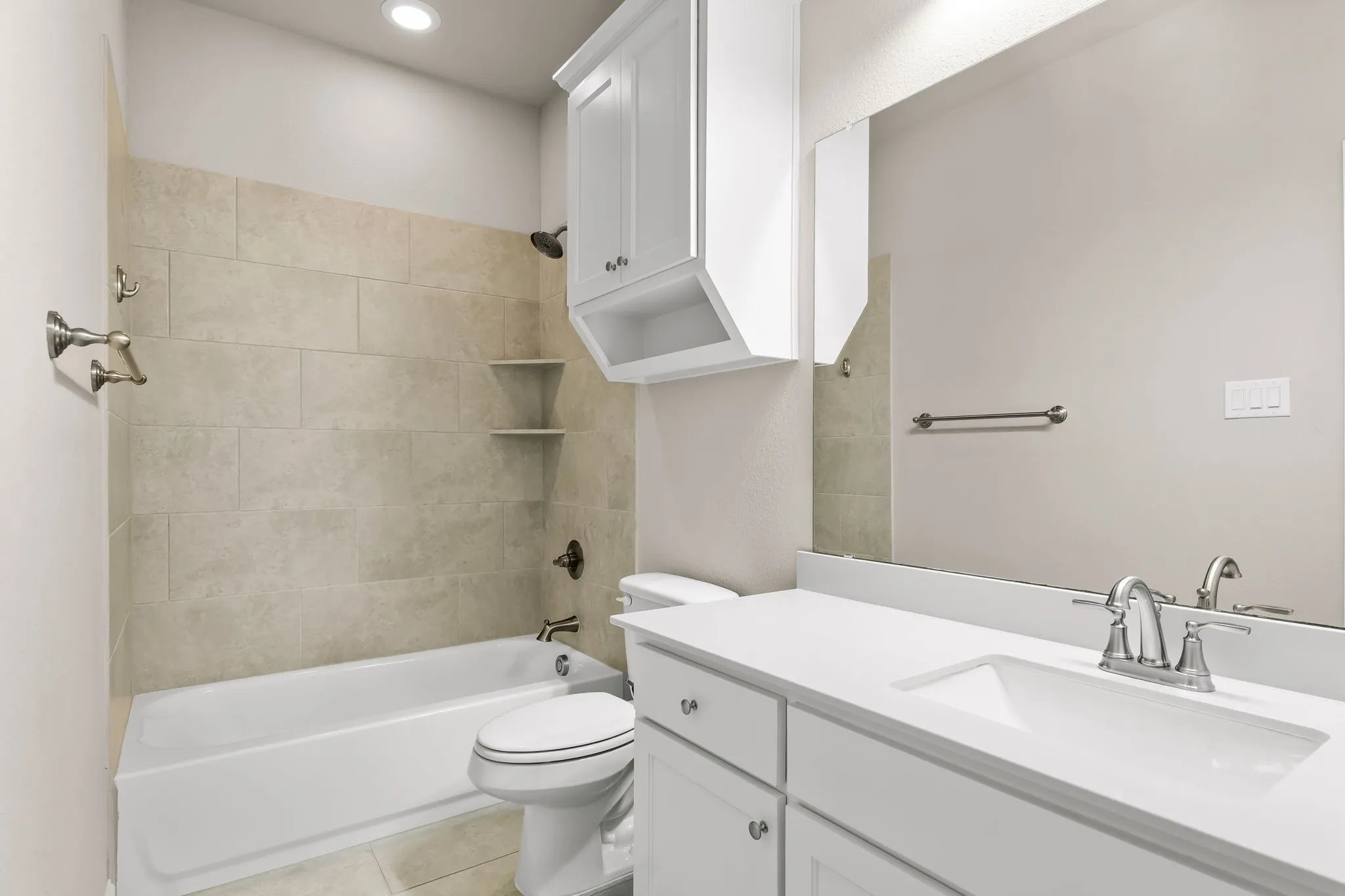 Bathroom featuring a white vanity with integrated sink, chrome faucet, and a large wall-mounted mirror