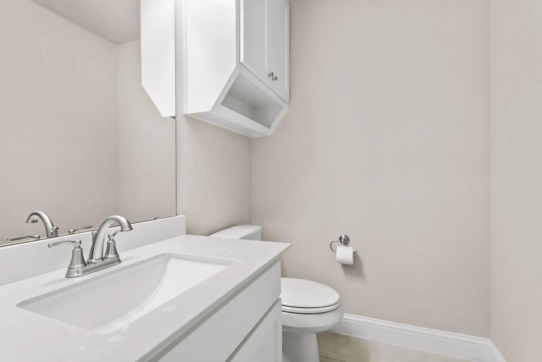 Bathroom vanity featuring an integrated rectangular sink, brushed nickel faucet, and white countertop