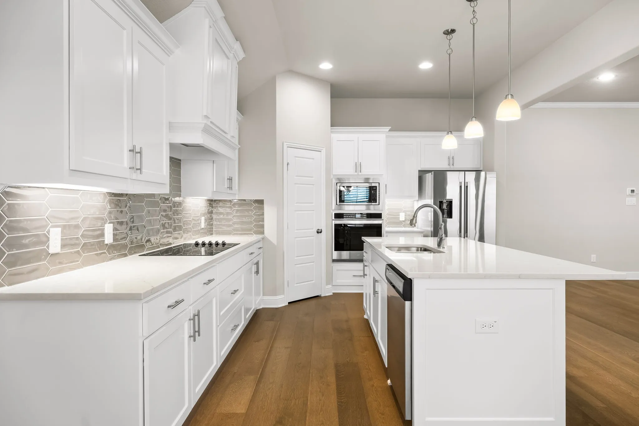 Modern kitchen featuring white cabinetry, light countertops, stainless steel appliances, a tile backsplash, and wood-finish flooring