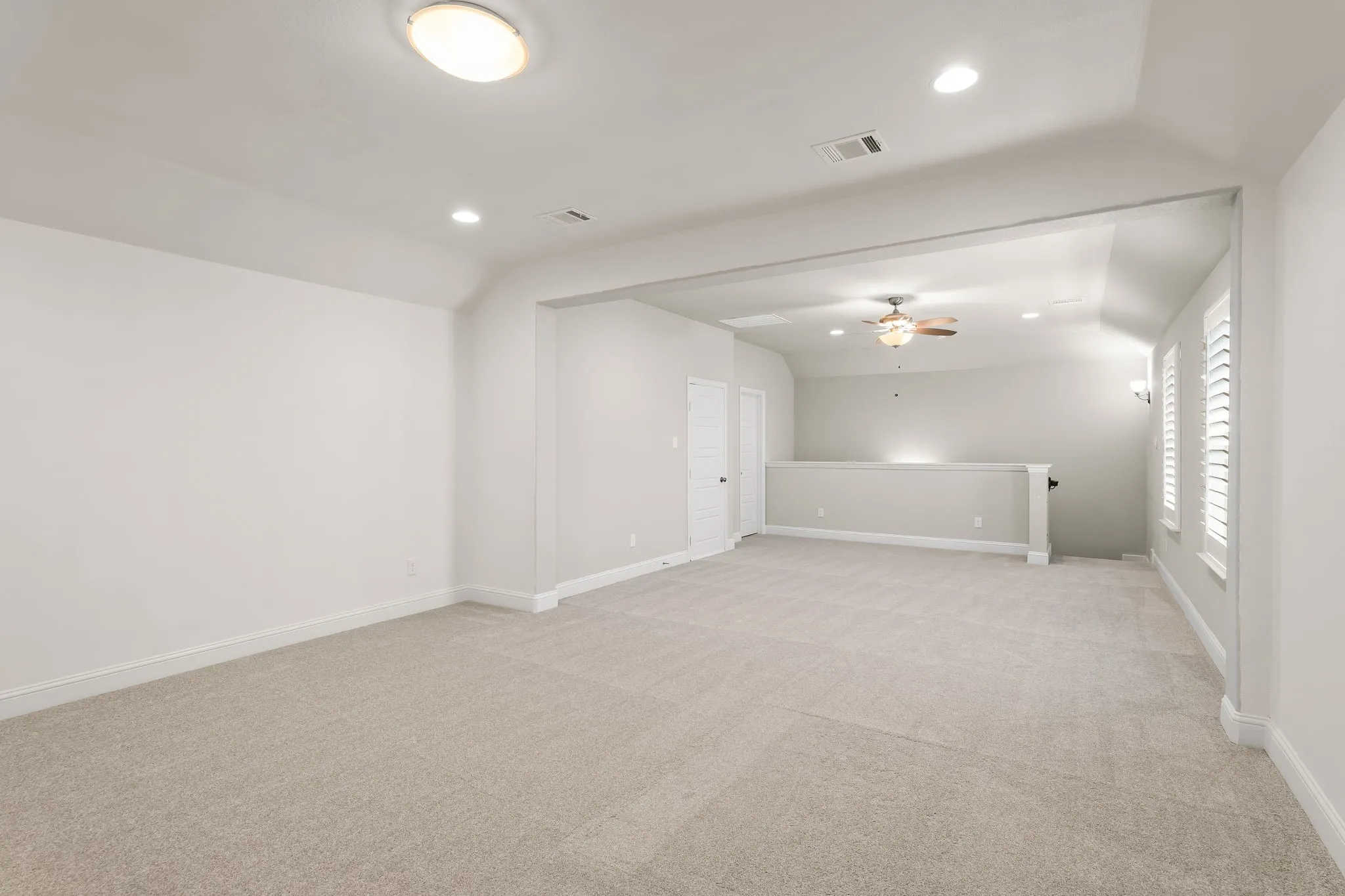 Expansive carpeted room featuring white walls, recessed lighting, and a ceiling fan