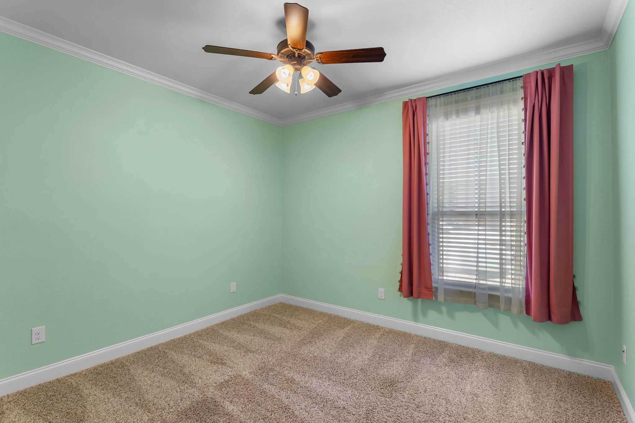 Bright room featuring soft green walls, a window with blinds, a ceiling fan with light fixture, and neutral-toned carpet flooring