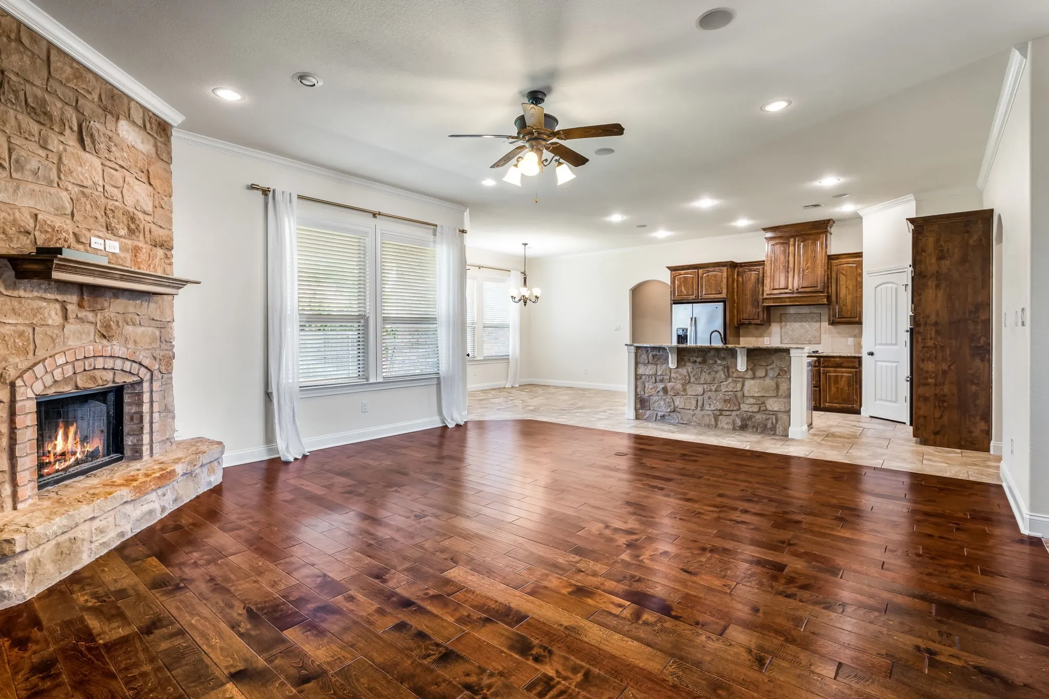 Spacious living area featuring rich wood-finish flooring and a stone-clad fireplace