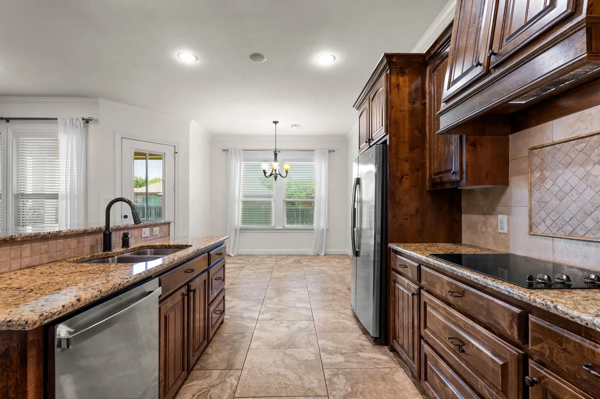 Kitchen featuring granite countertops, dark wood cabinetry, stainless steel appliances, tile flooring, and a tile backsplash