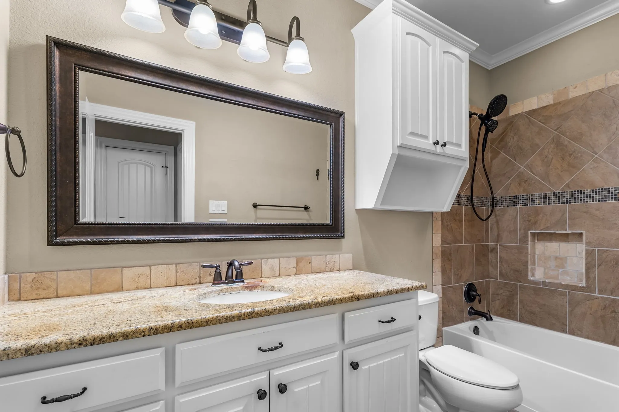 Bathroom vanity featuring a granite countertop, undermount sink, and dark bronze faucet