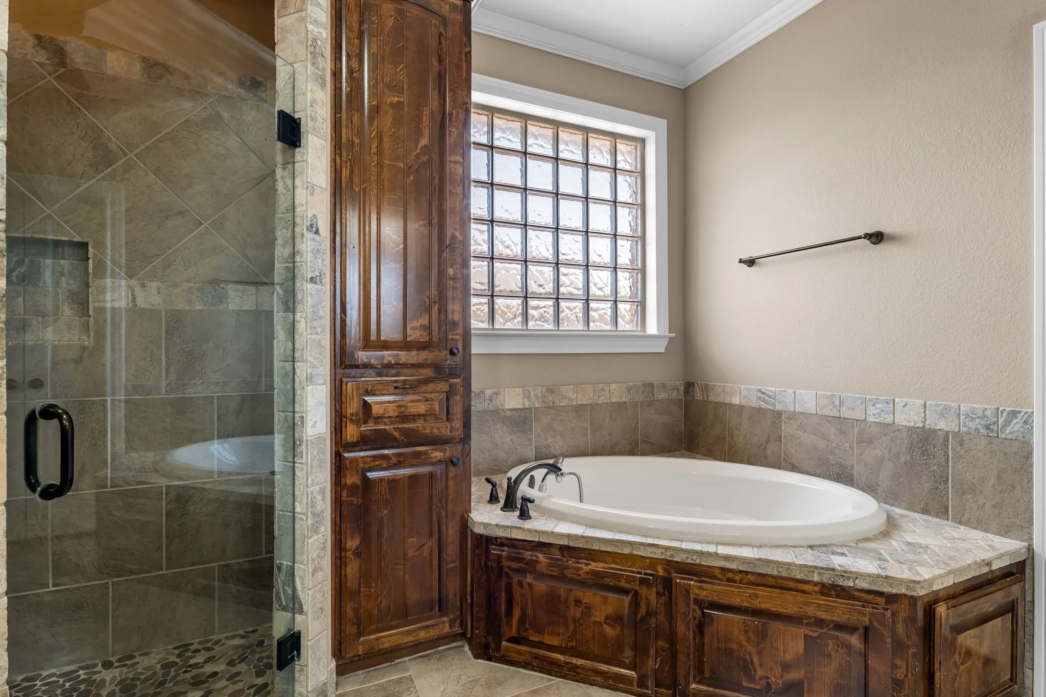 Soaking tub with a natural stone surround and dark wood cabinetry