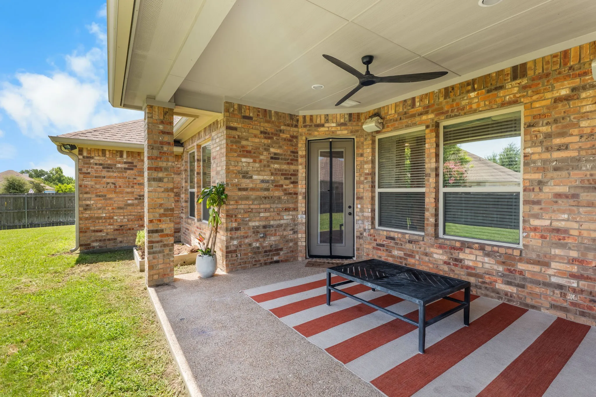 Covered patio featuring a ceiling fan, recessed lighting, brick exterior walls, and a glass-paneled door