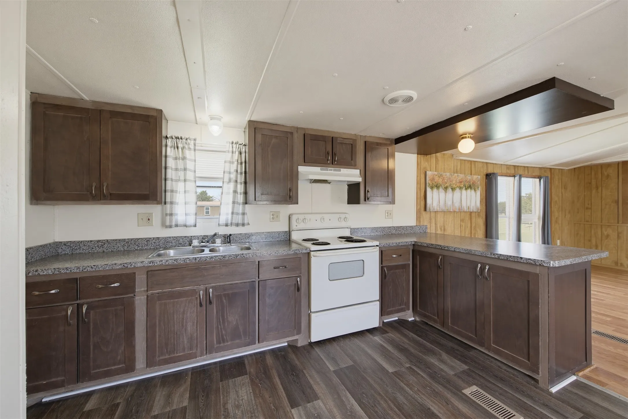 Kitchen featuring dark wood-finish cabinetry, light-toned countertops, and wood-finish flooring